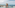 Family on glass skywalk overlooking panoramic ocean and cityscape.