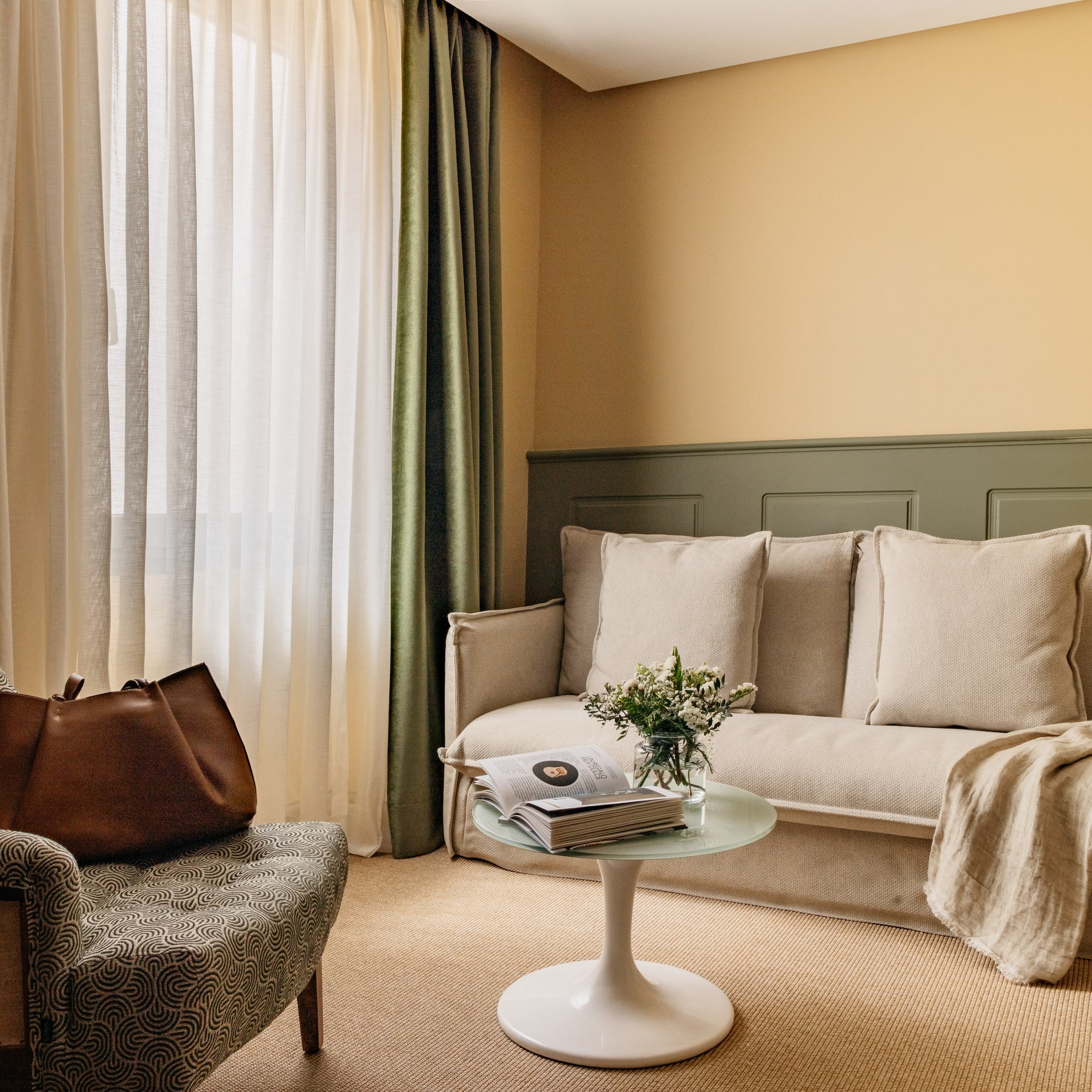 Decoración moderna de sala con sofá beige, sillón y paredes bicolor.