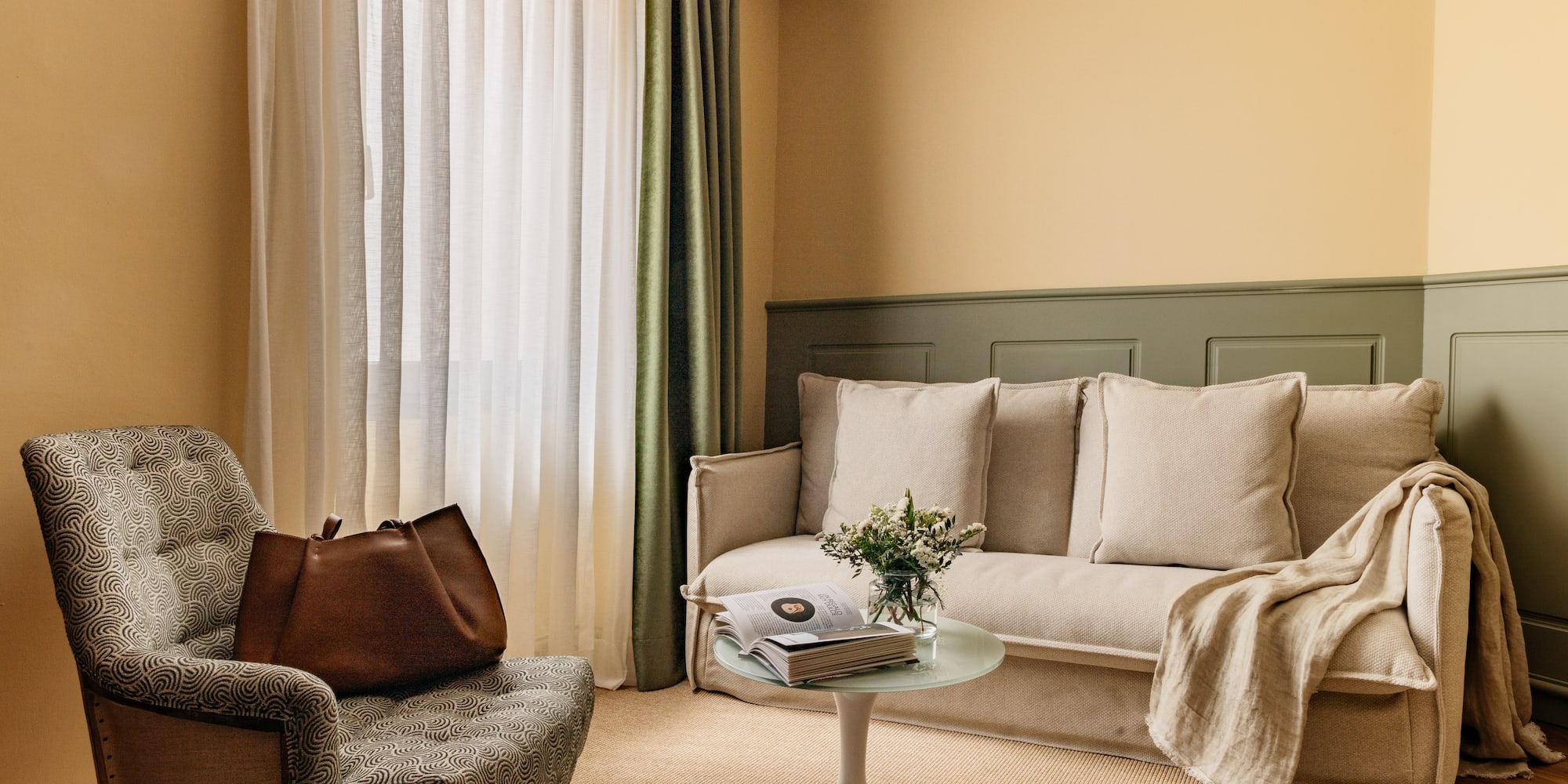 Decoración moderna de sala con sofá beige, sillón y paredes bicolor.