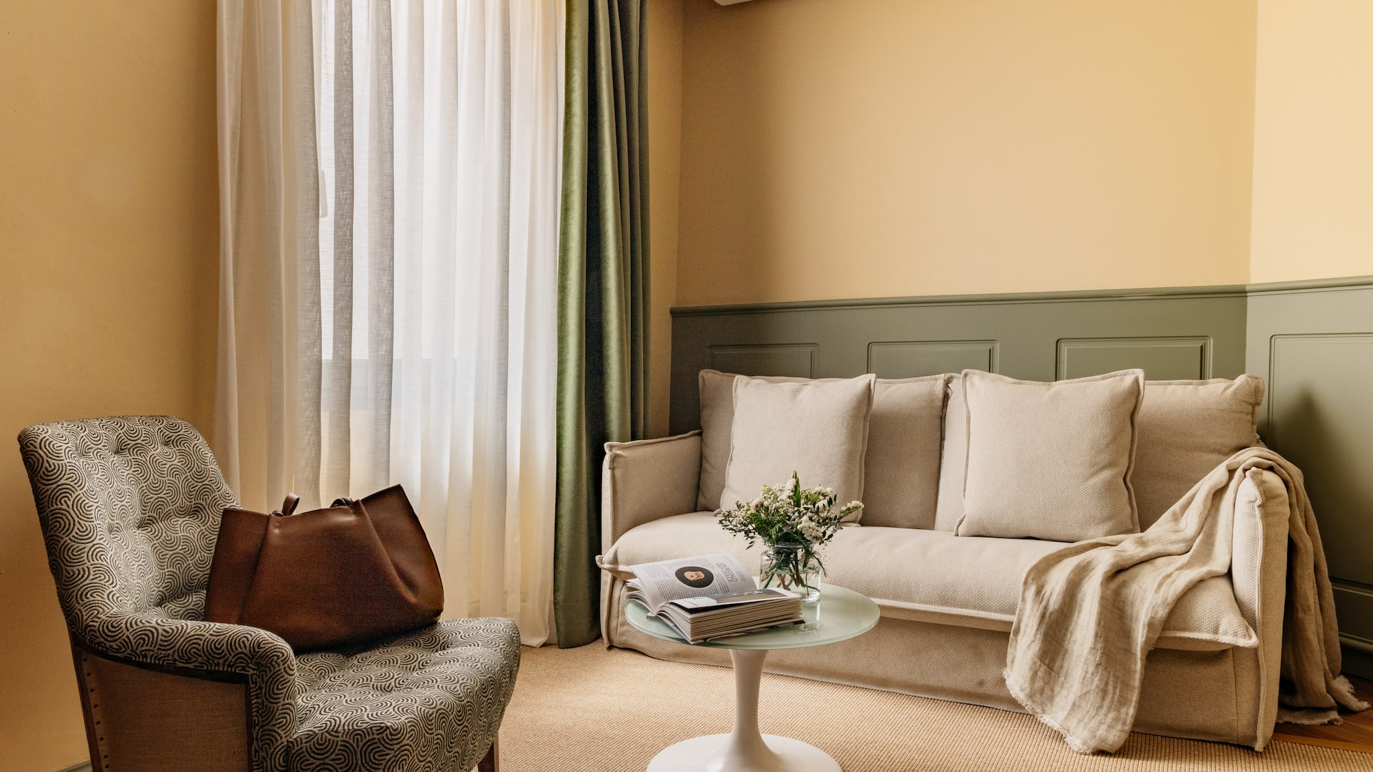 Decoración moderna de sala con sofá beige, sillón y paredes bicolor.