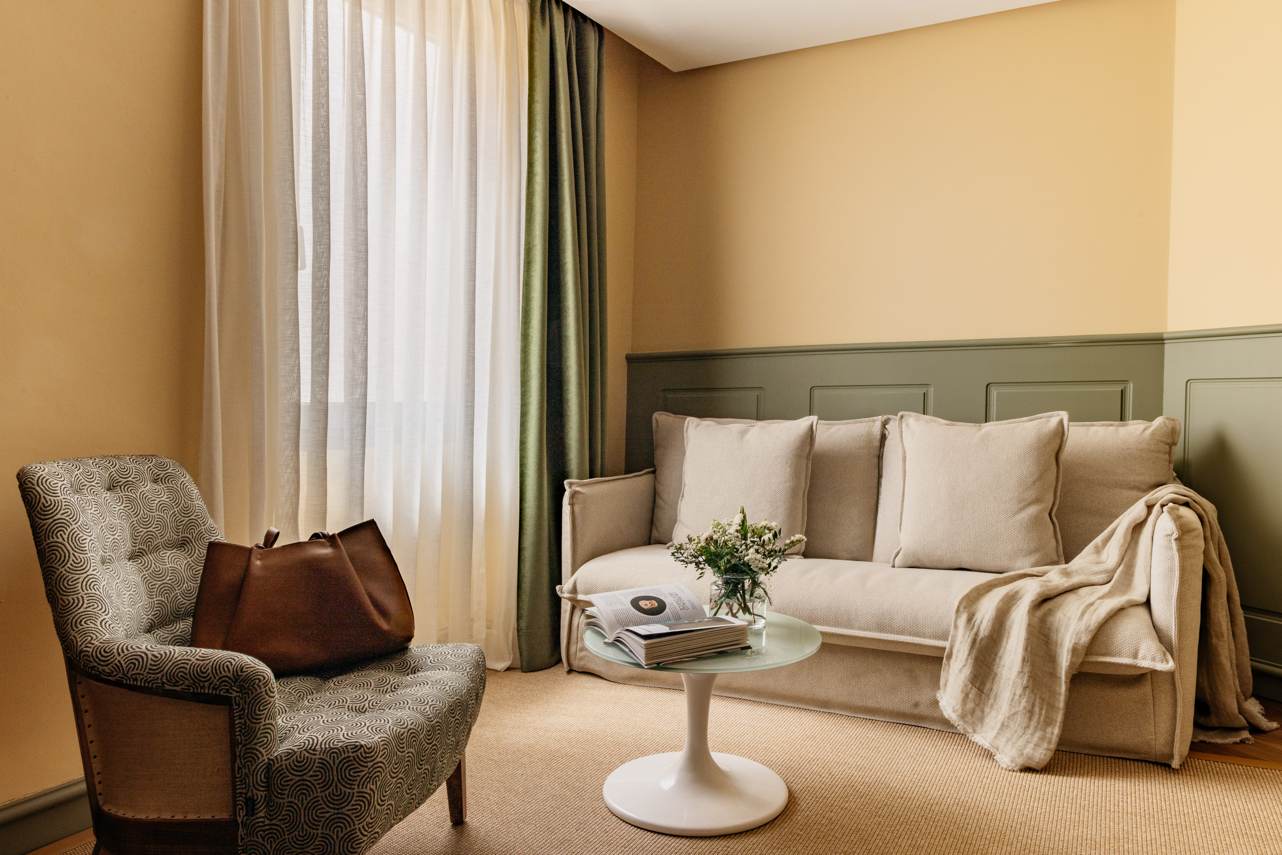 Decoración moderna de sala con sofá beige, sillón y paredes bicolor.