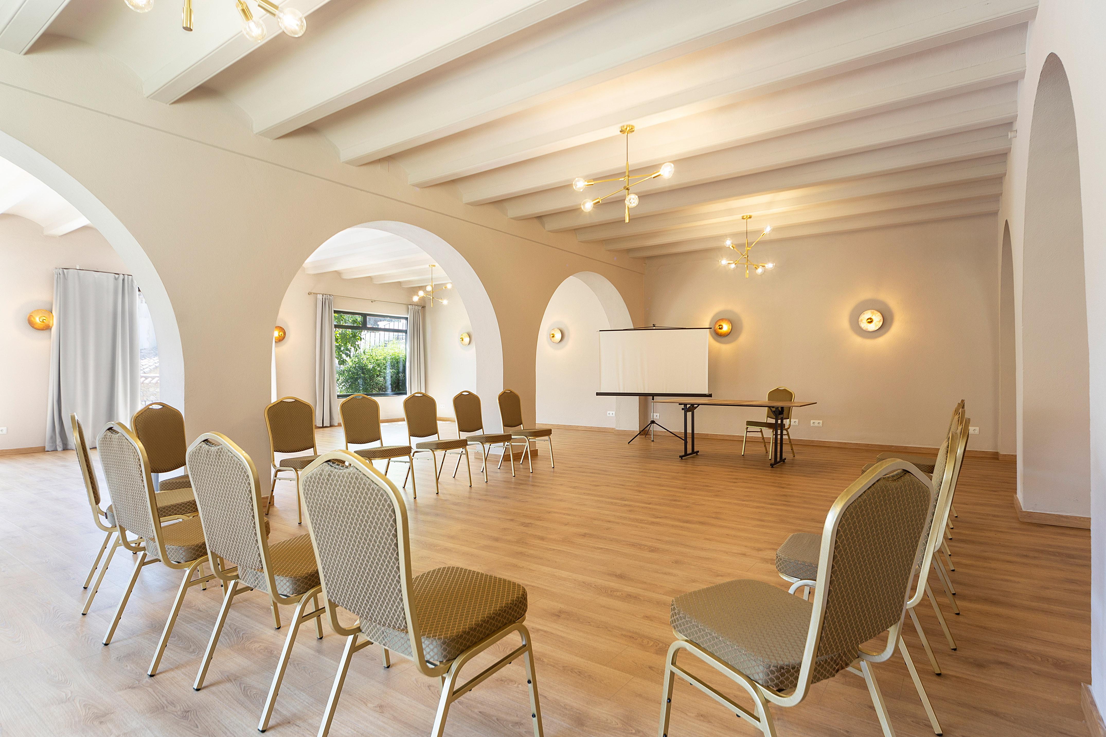 Modern conference room with chairs, projector screen, arched walls, and wooden floor.