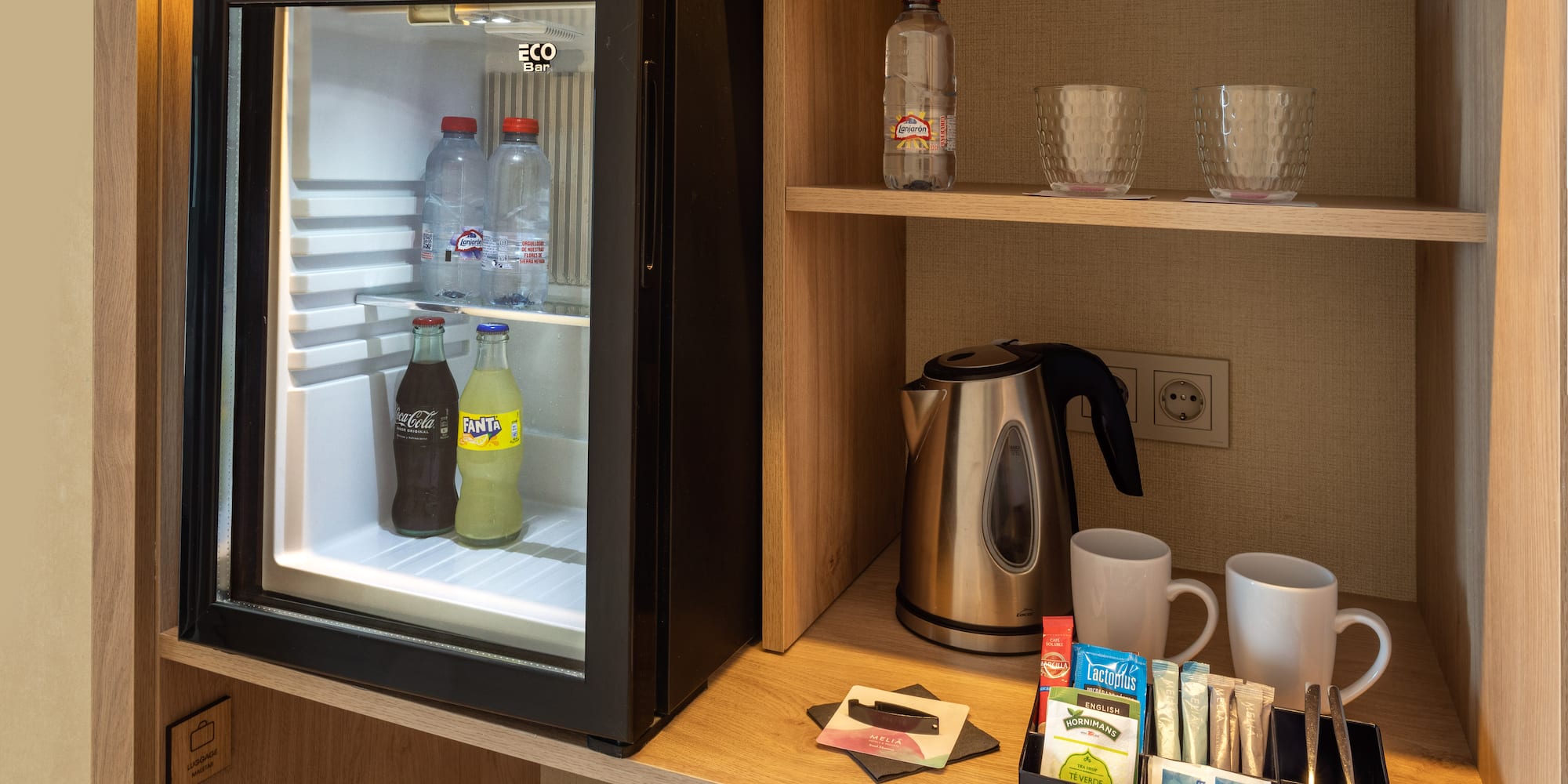 a small refrigerator with drinks and cups on a shelf
