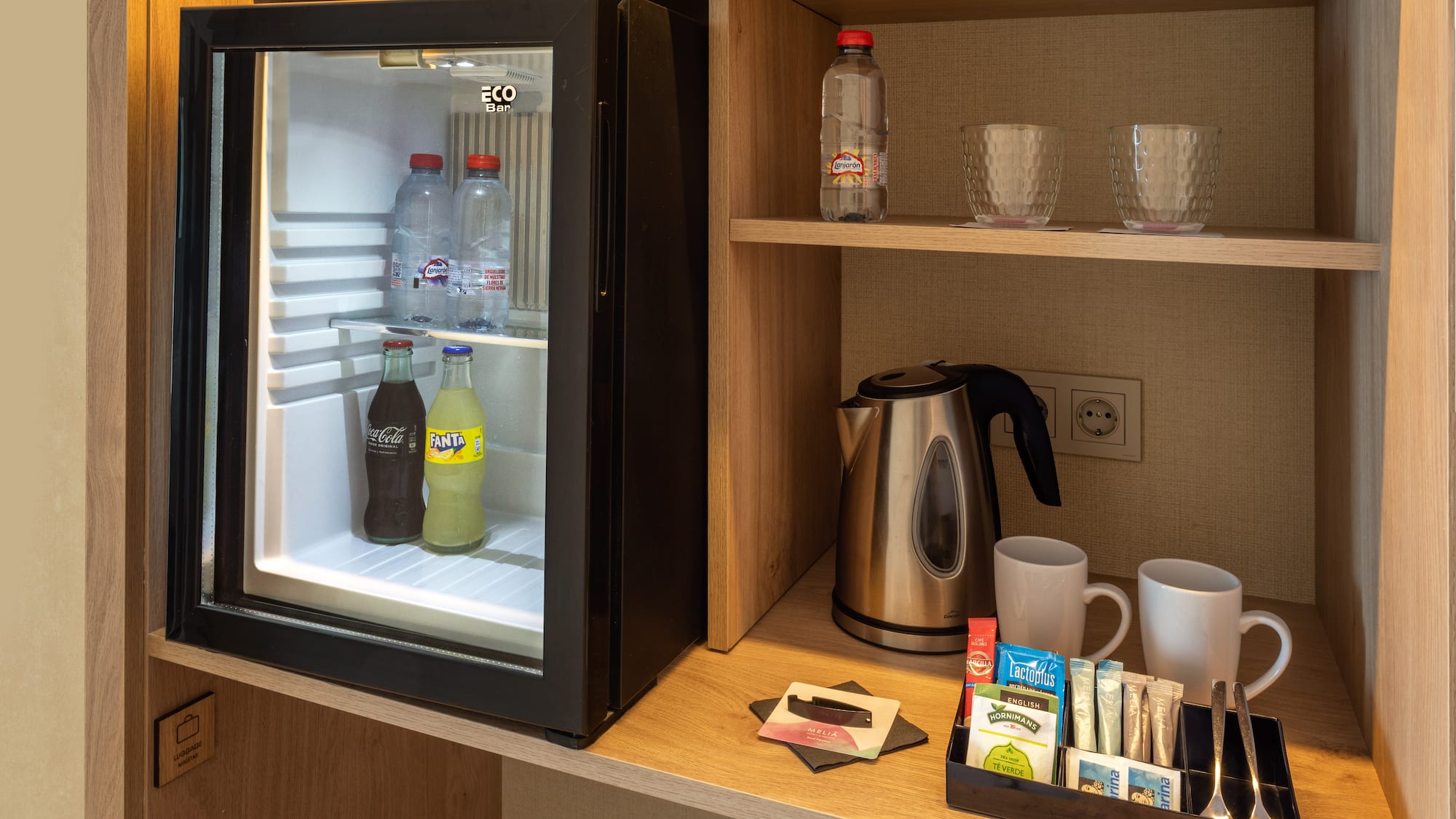 a small refrigerator with drinks and cups on a shelf