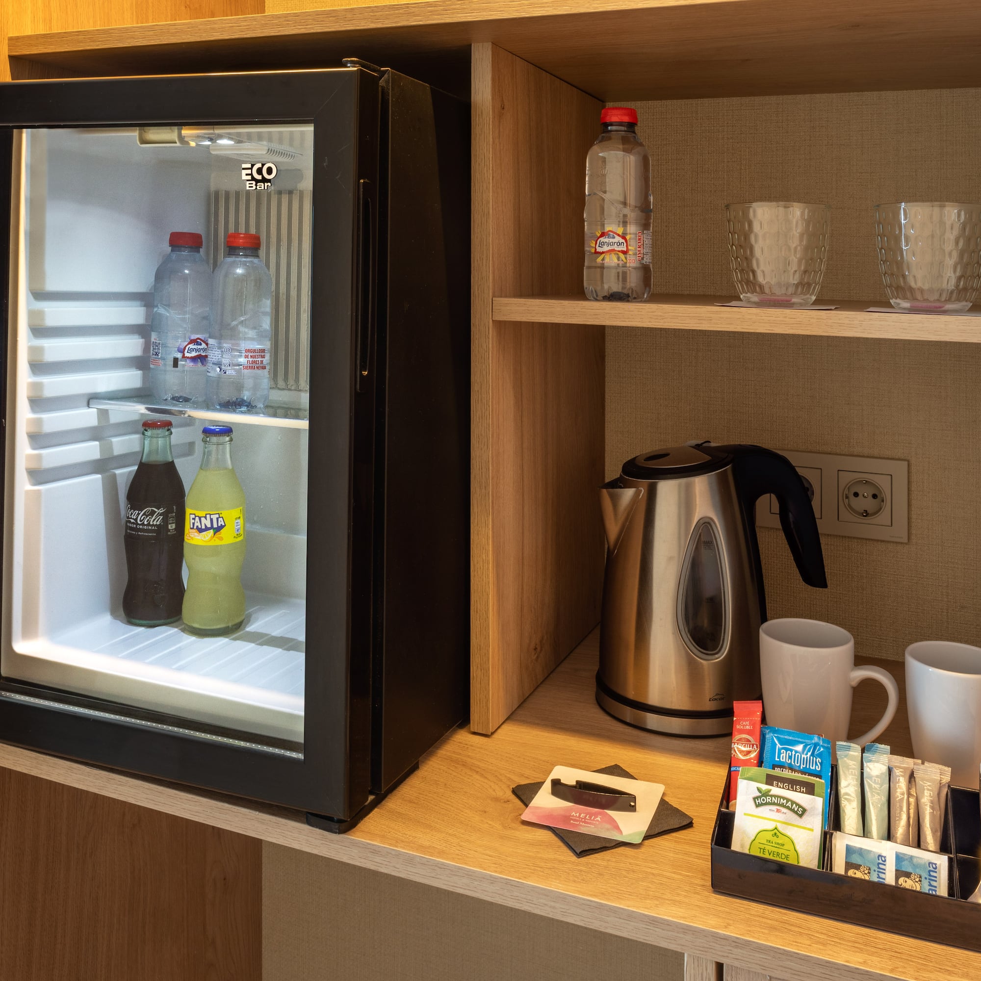 a small refrigerator with drinks and cups on a shelf