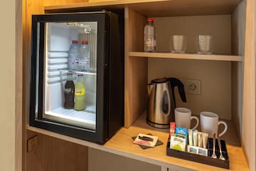 a small refrigerator with drinks and cups on a shelf