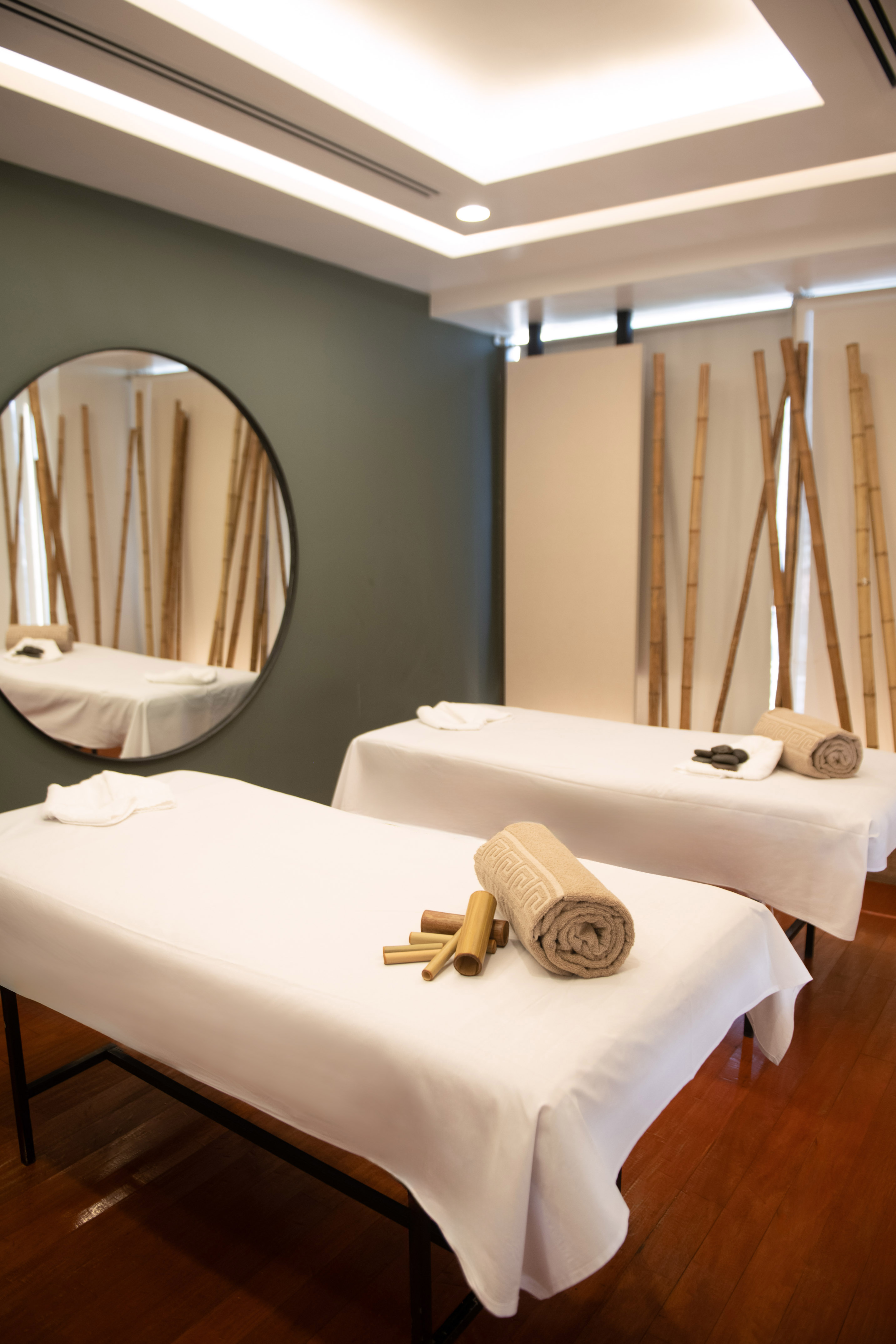 Spa room with two massage tables, rolled towels, and bamboo accents.