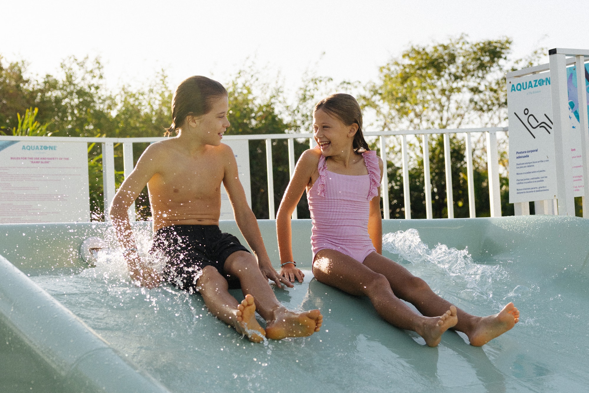 Happy children splashing on water slide at Aquazone water park.