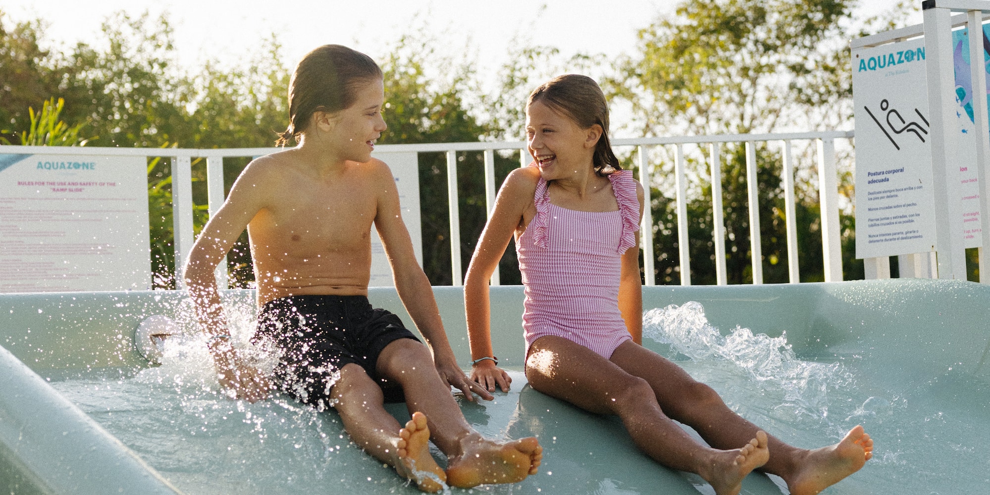 Happy children splashing down a water slide at an Aquazone.