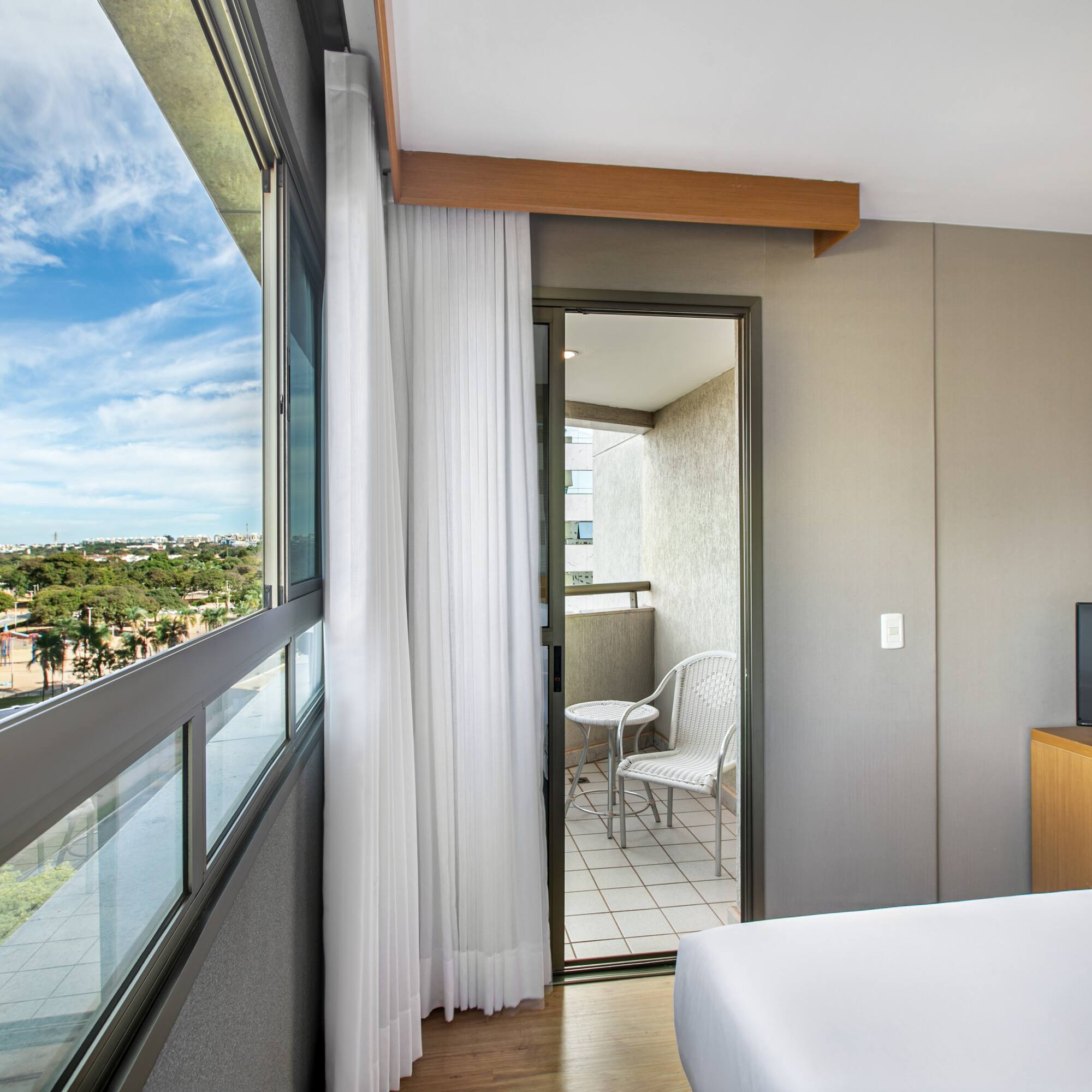 Hotel room with panoramic city view, balcony, and distant Ferris wheel.