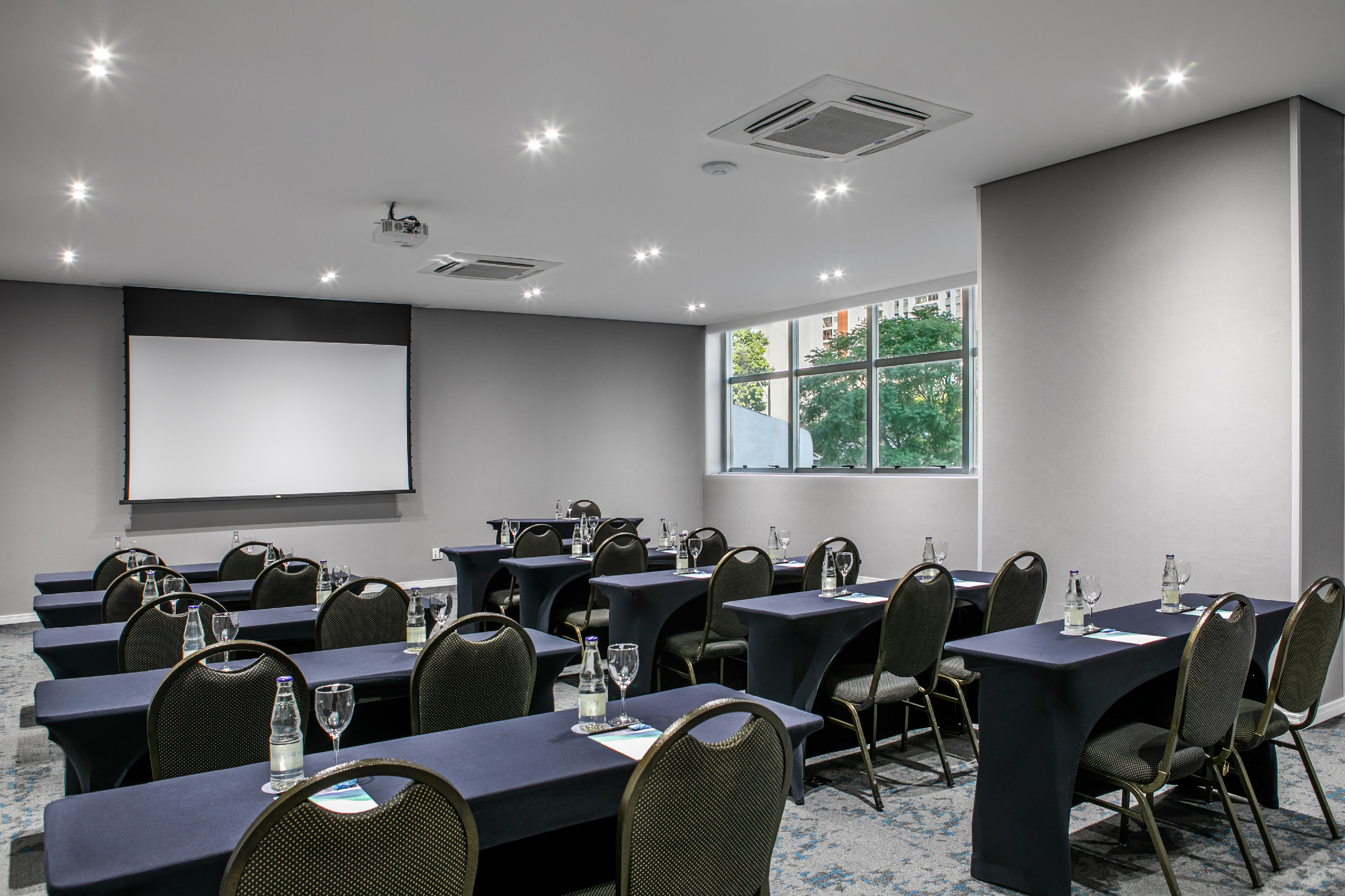 Modern meeting room with tables, chairs, projection screen, and window. - Jequitibá - Meliá Jardim Europa, Sao Paulo