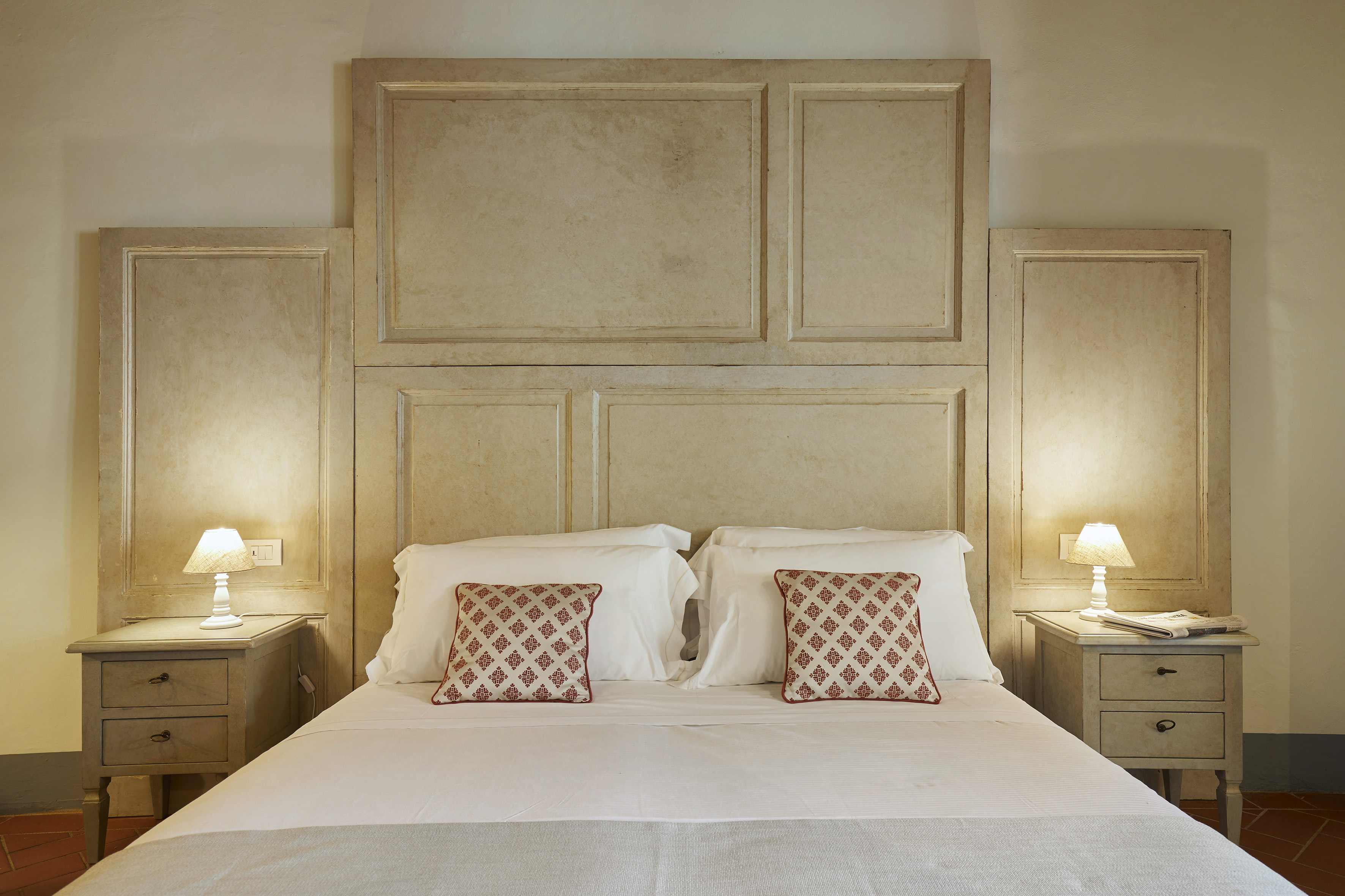 Bedroom with white bed, distressed panel headboard, nightstands, and lamps.