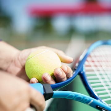 a person holding a tennis racket and a ball