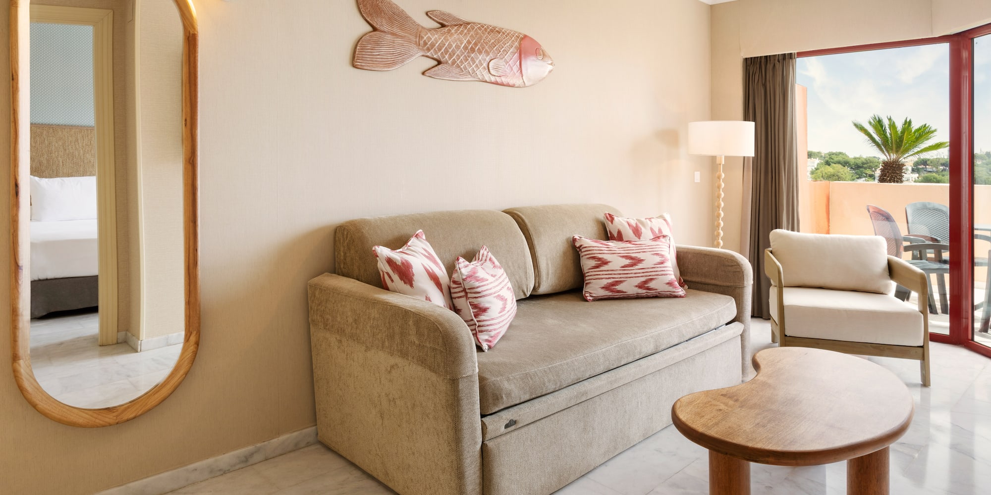 Hotel suite living room with sofa bed, balcony, and tropical fish decor.