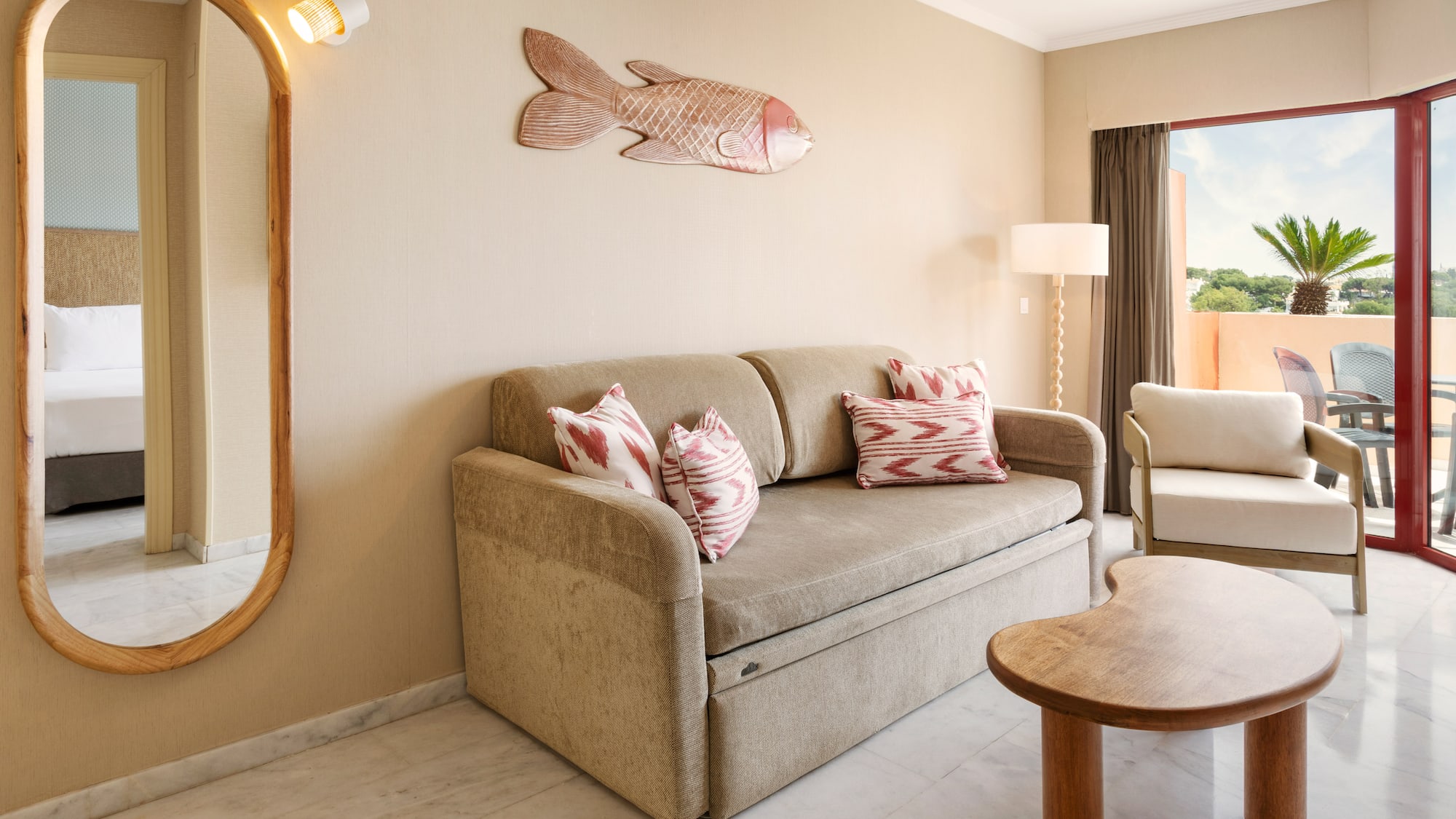 Hotel suite living room with sofa bed, tropical fish decor, and balcony.