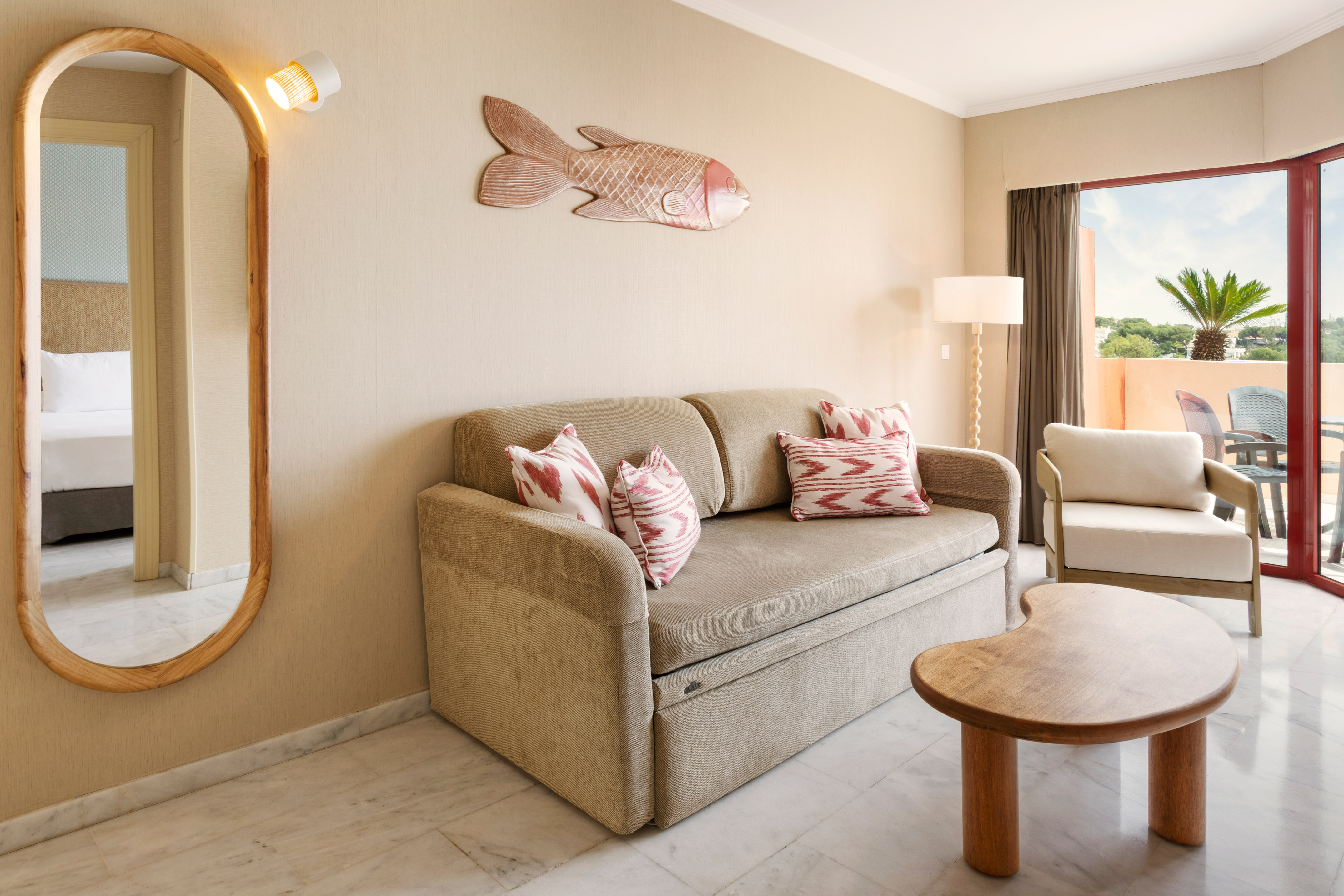 Hotel suite living room with sofa bed, tropical fish decor, and balcony.