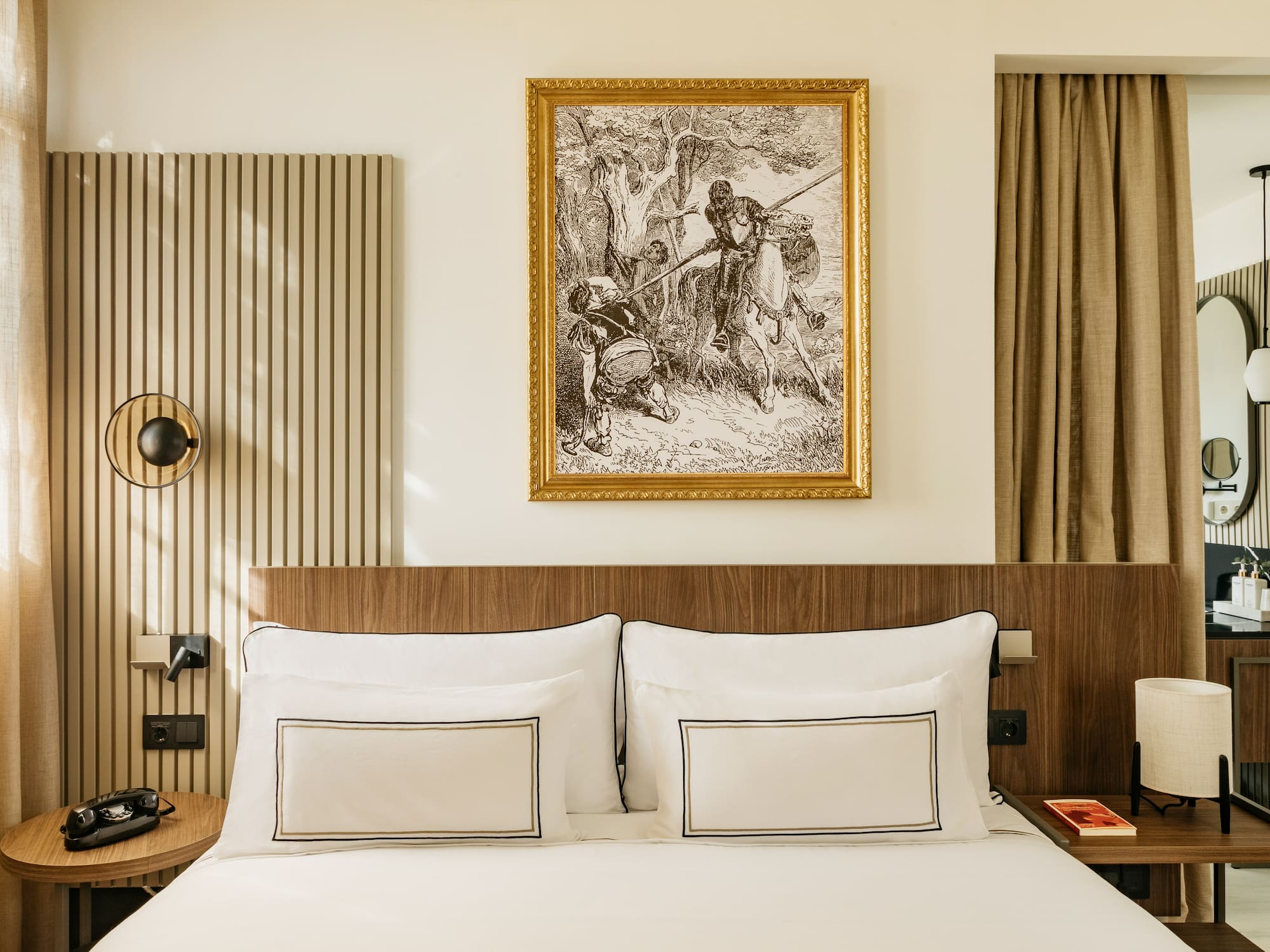 Modern hotel bedroom with white bed, wood headboard, and framed historical artwork.