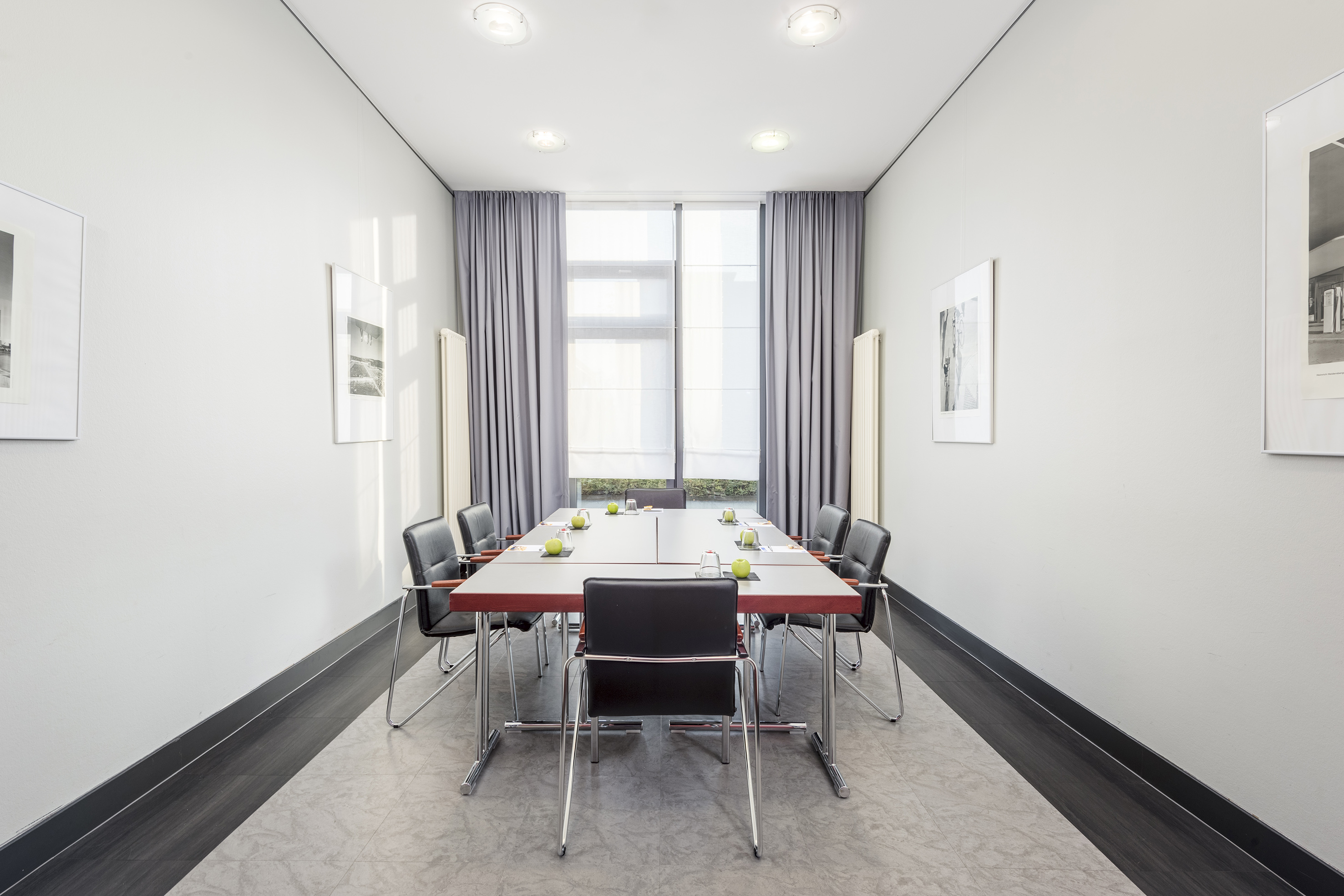 Modern professional meeting room with long table, chairs, bright window.