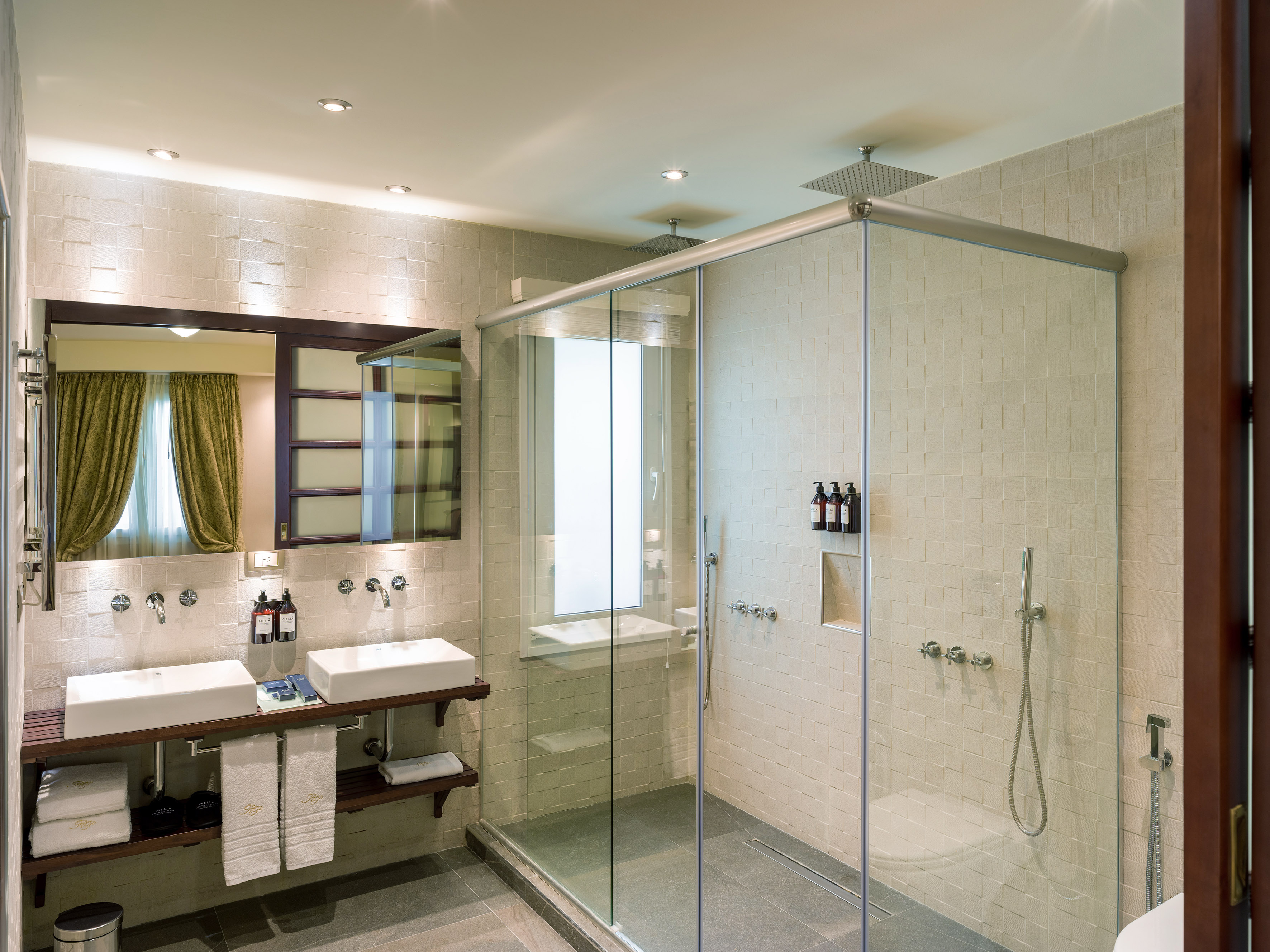 Bright modern bathroom with double vanity sinks and large glass shower.