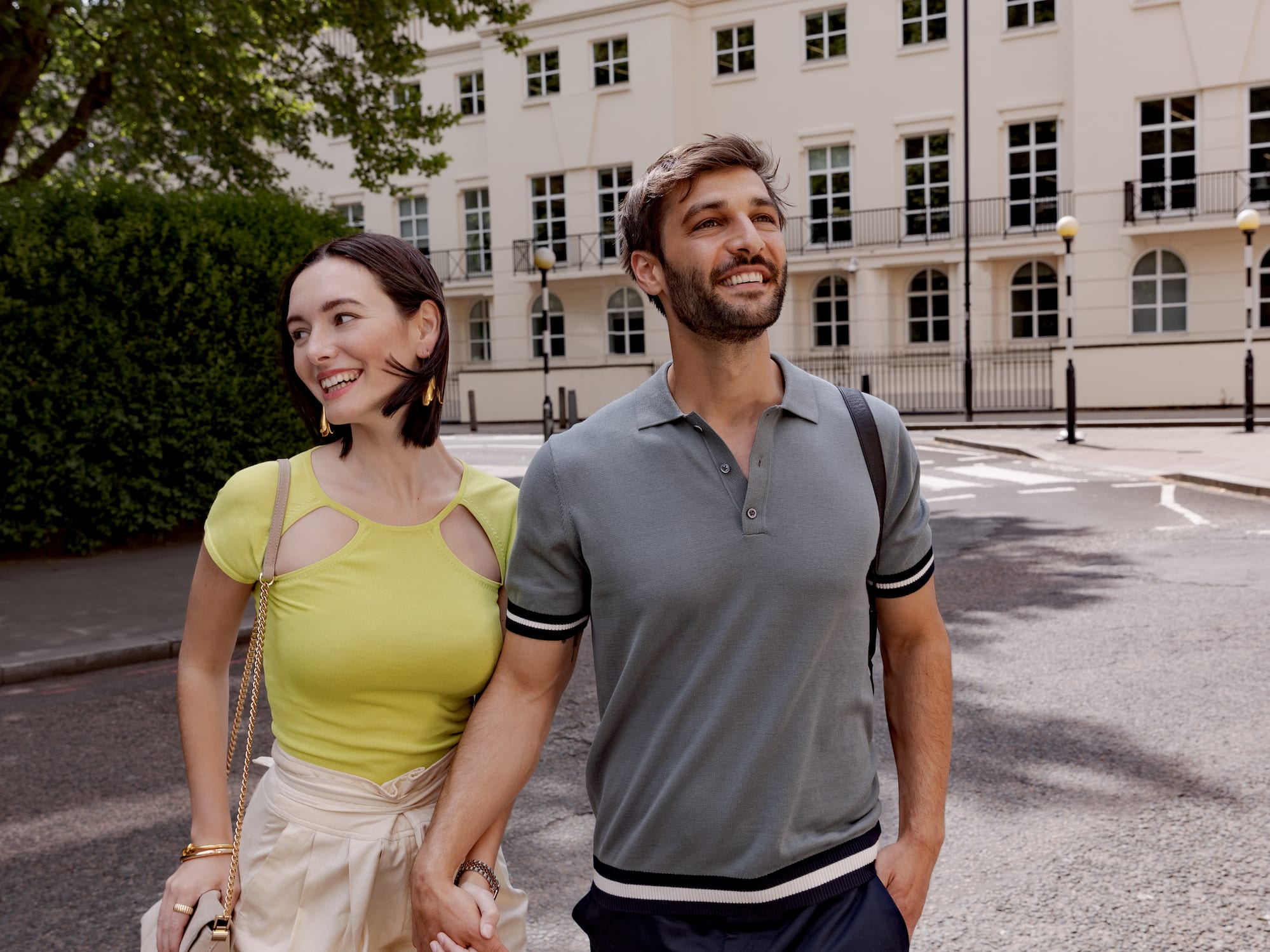 A man and a woman walk hand in hand down a street.