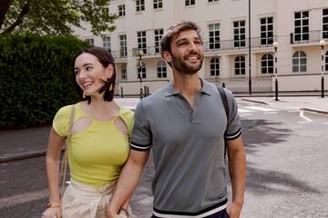 a man and woman holding hands and walking on a street