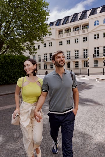 a man and woman holding hands and walking on a street