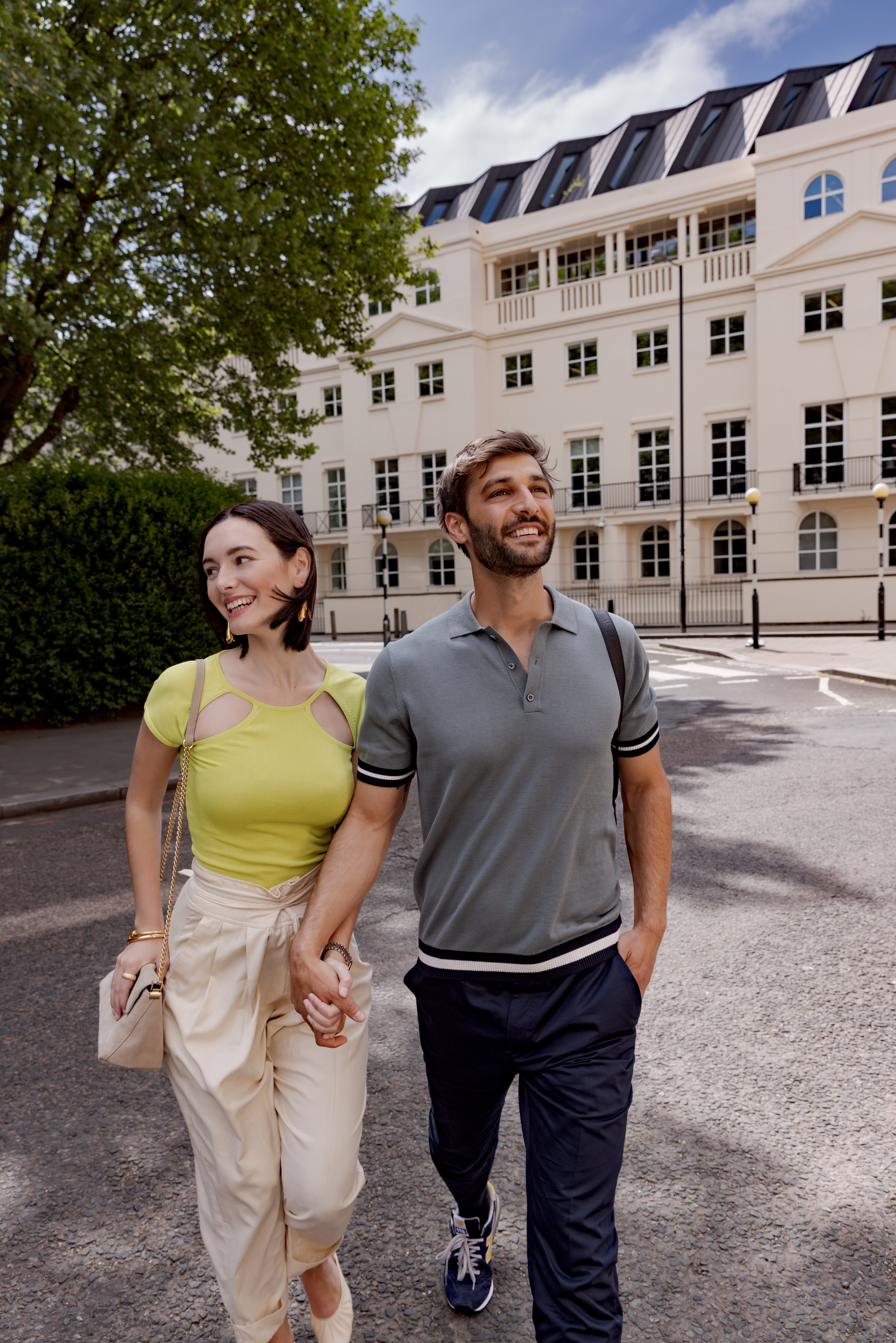 A man and a woman walk hand in hand down a street.