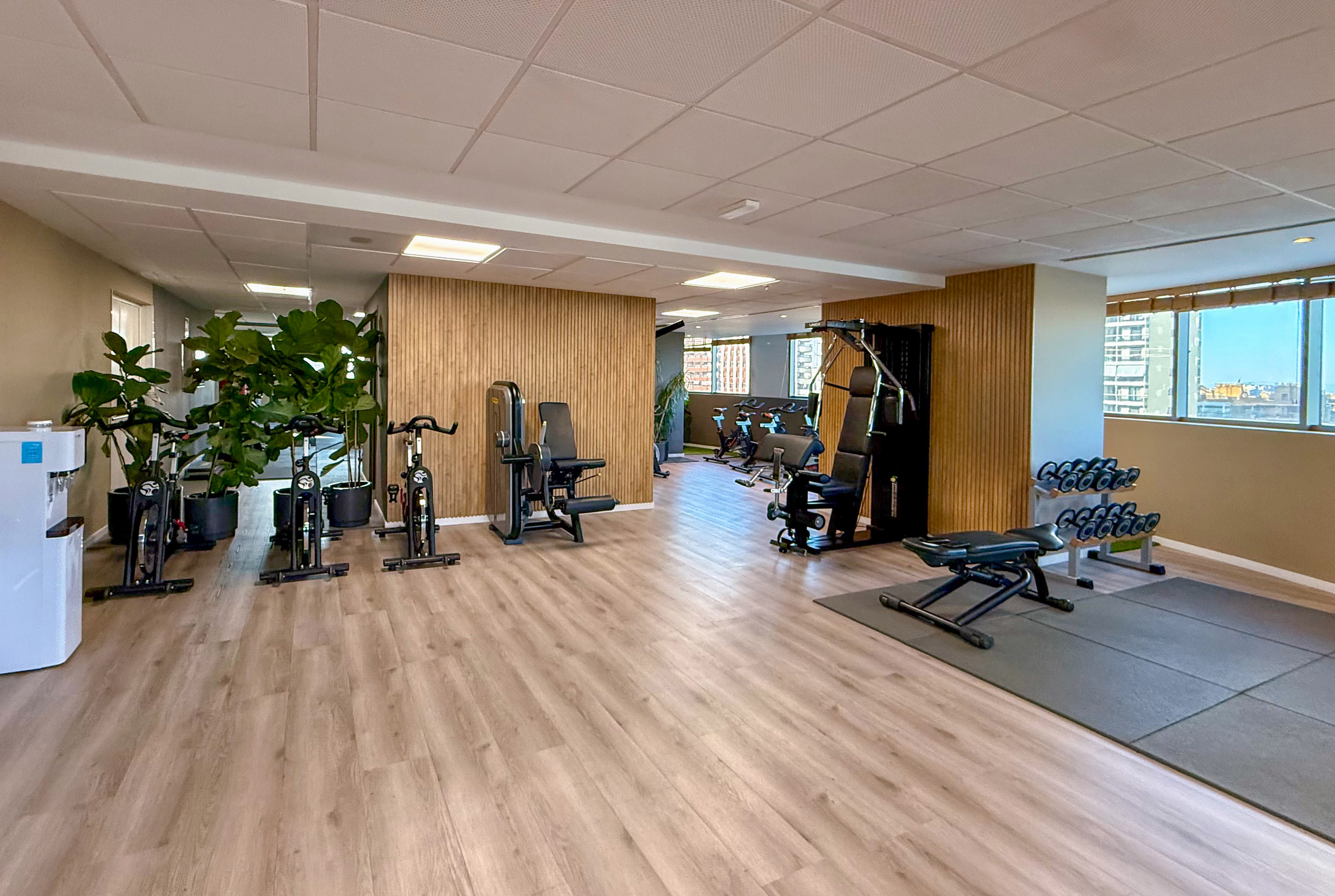 Modern gym with exercise bikes, weight machines, and dumbbells.