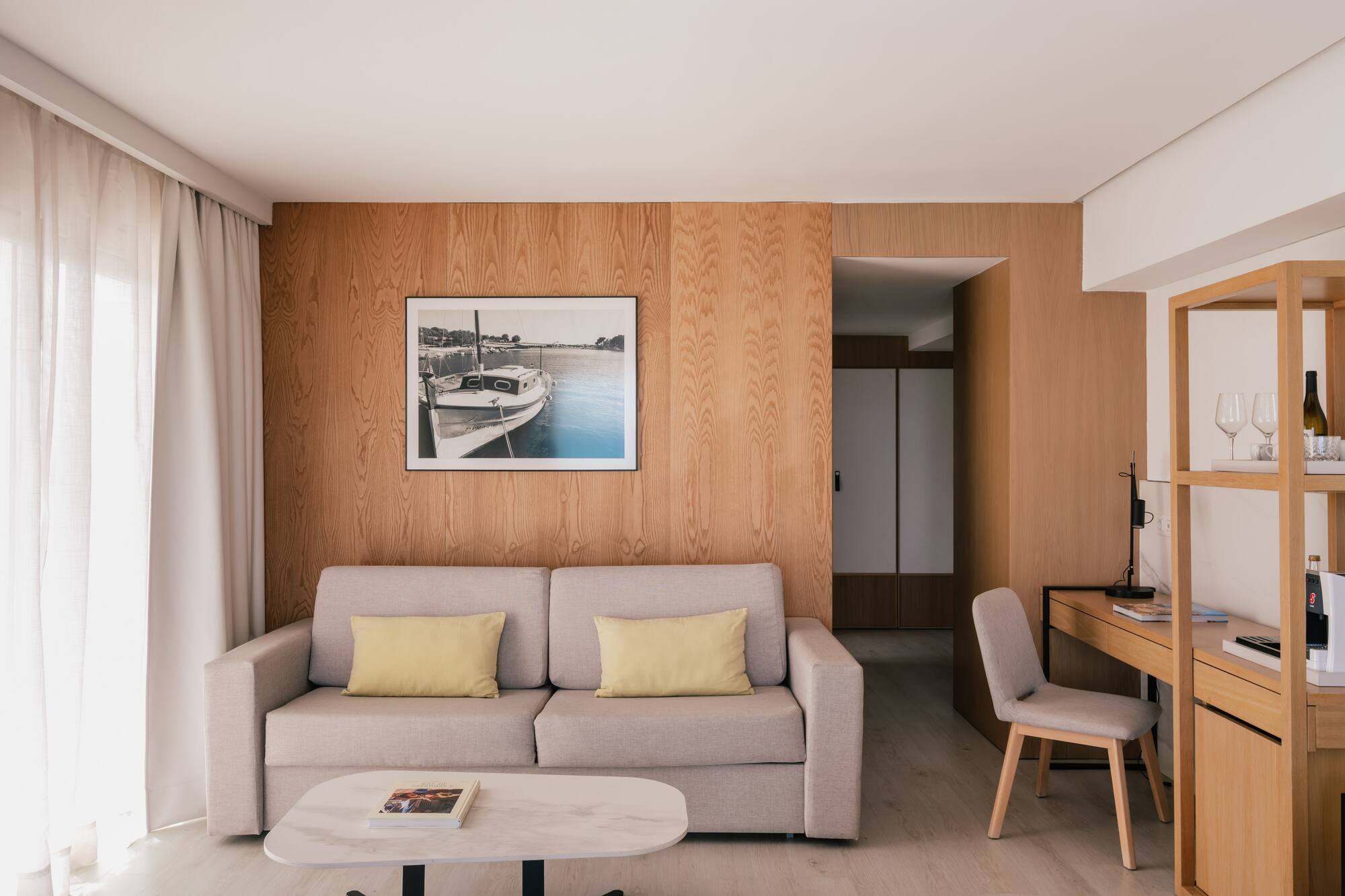 Salón de suite moderno con sofá, pared de madera y escritorio.