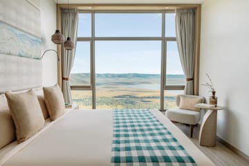 a room with a bed and chairs and a view of the valley