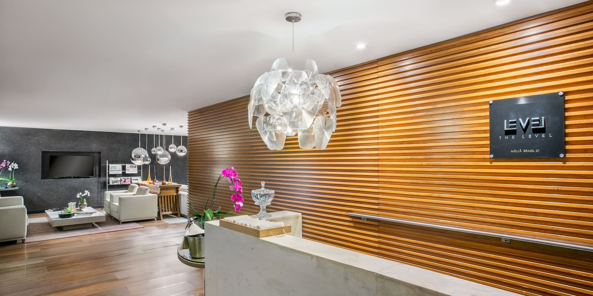 Sleek hotel reception with "The Level" sign, marble desk, wood wall, and lounge.