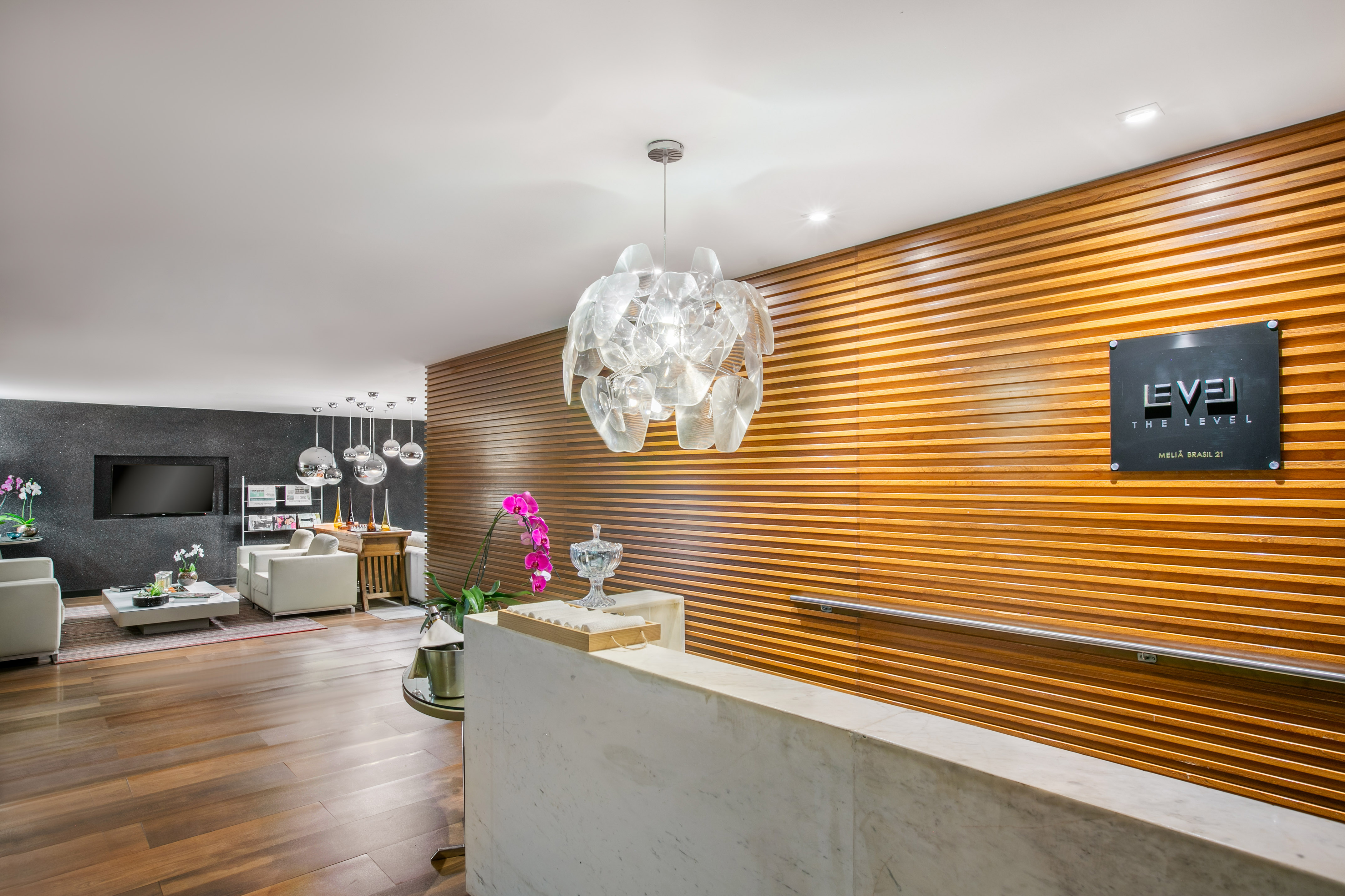 Sleek hotel reception with "The Level" sign, marble desk, wood wall, and lounge.