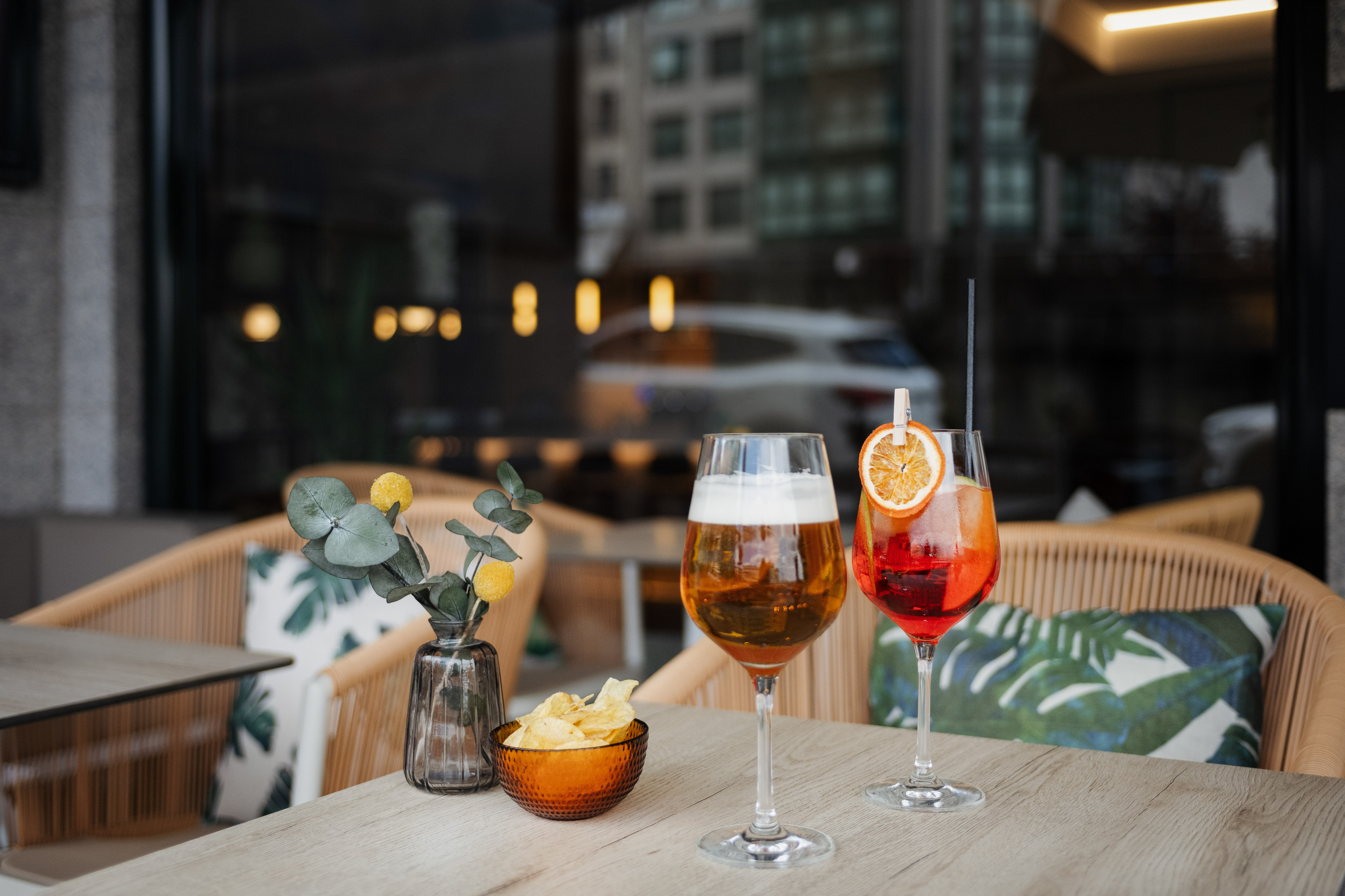 Aperol Spritz and beer with chips on an outdoor cafe table.