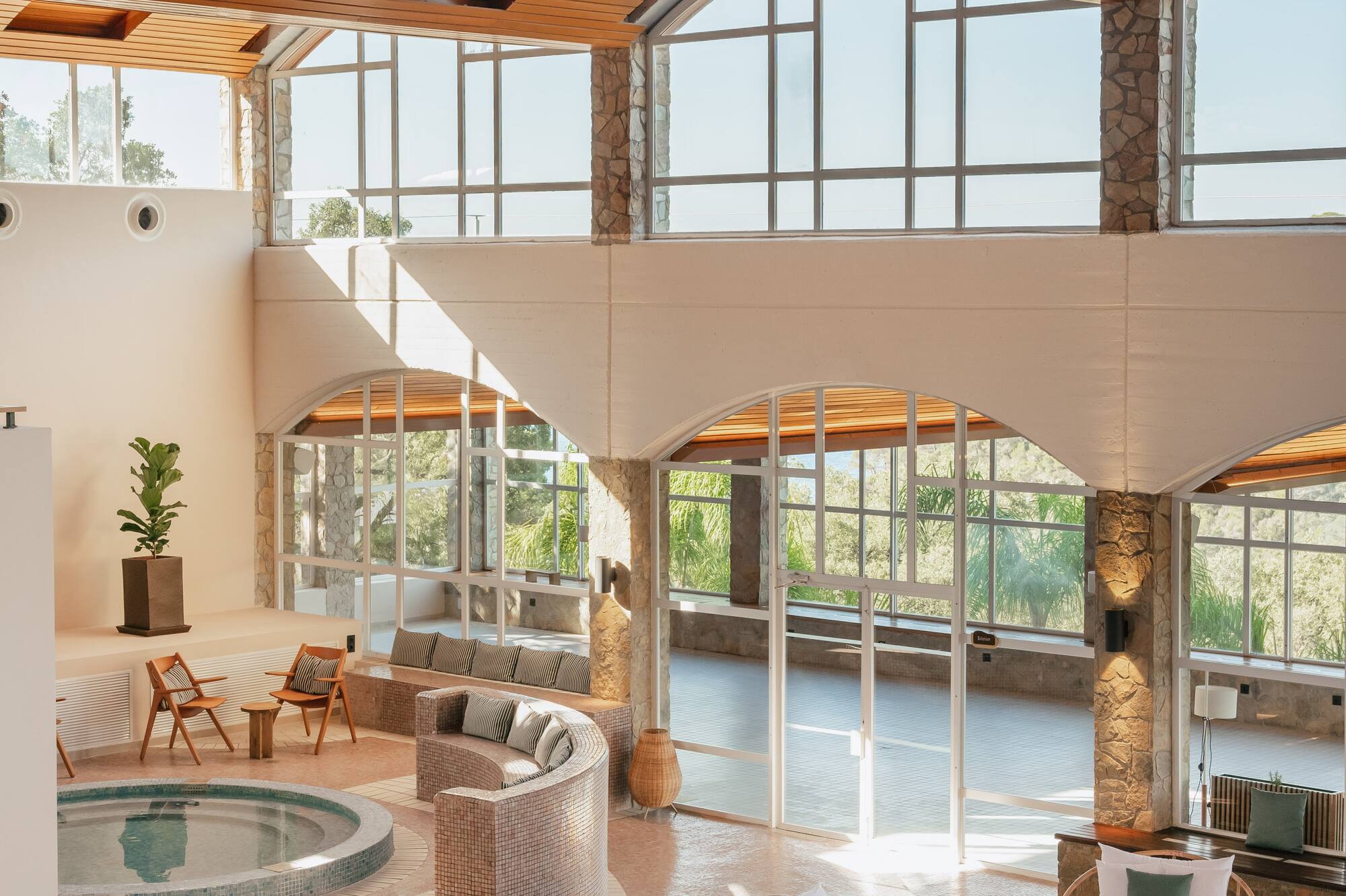 Indoor spa with pool, hot tub, modern seating, and arched wooden ceiling.