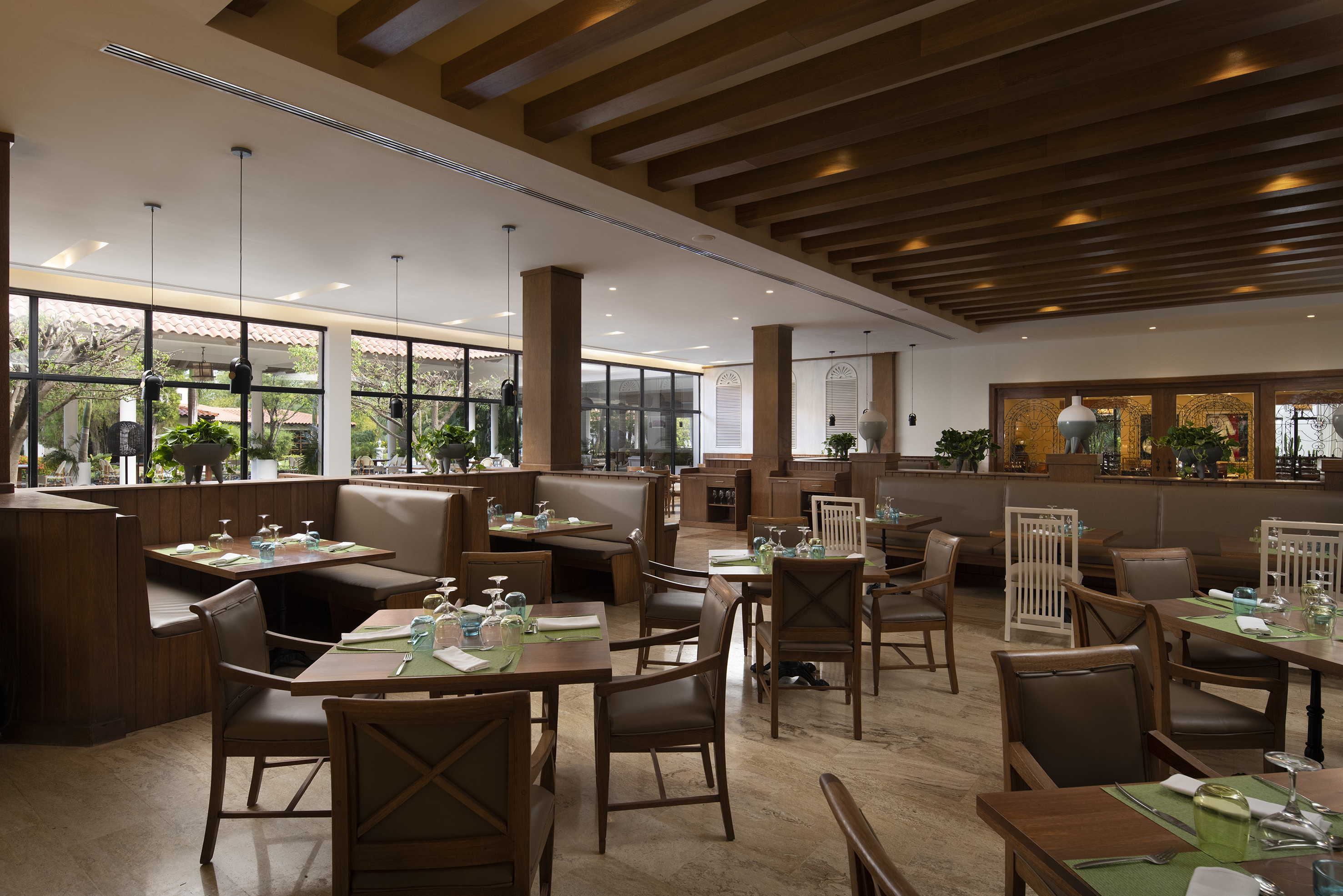 Modern restaurant dining room with wooden tables, booths, and large windows.