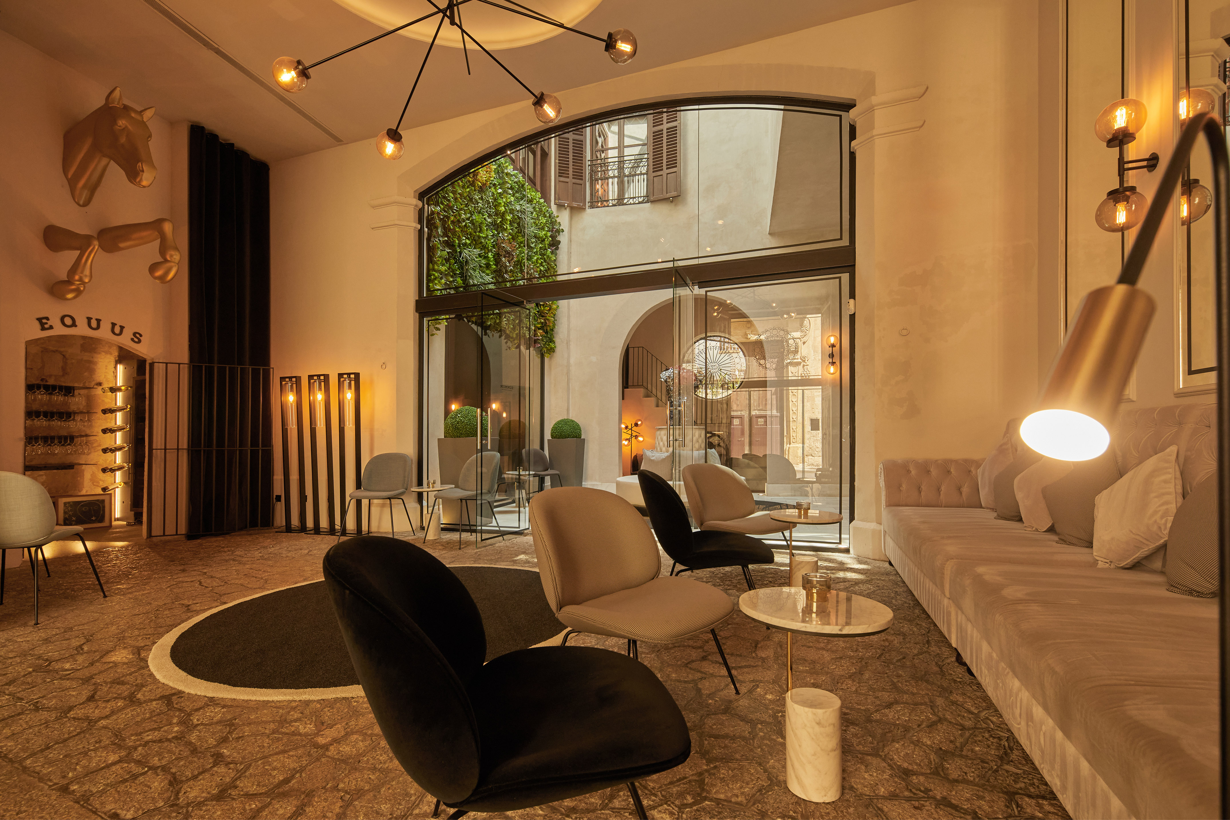 Hotel lounge with equestrian sculpture, modern furniture, and courtyard view.