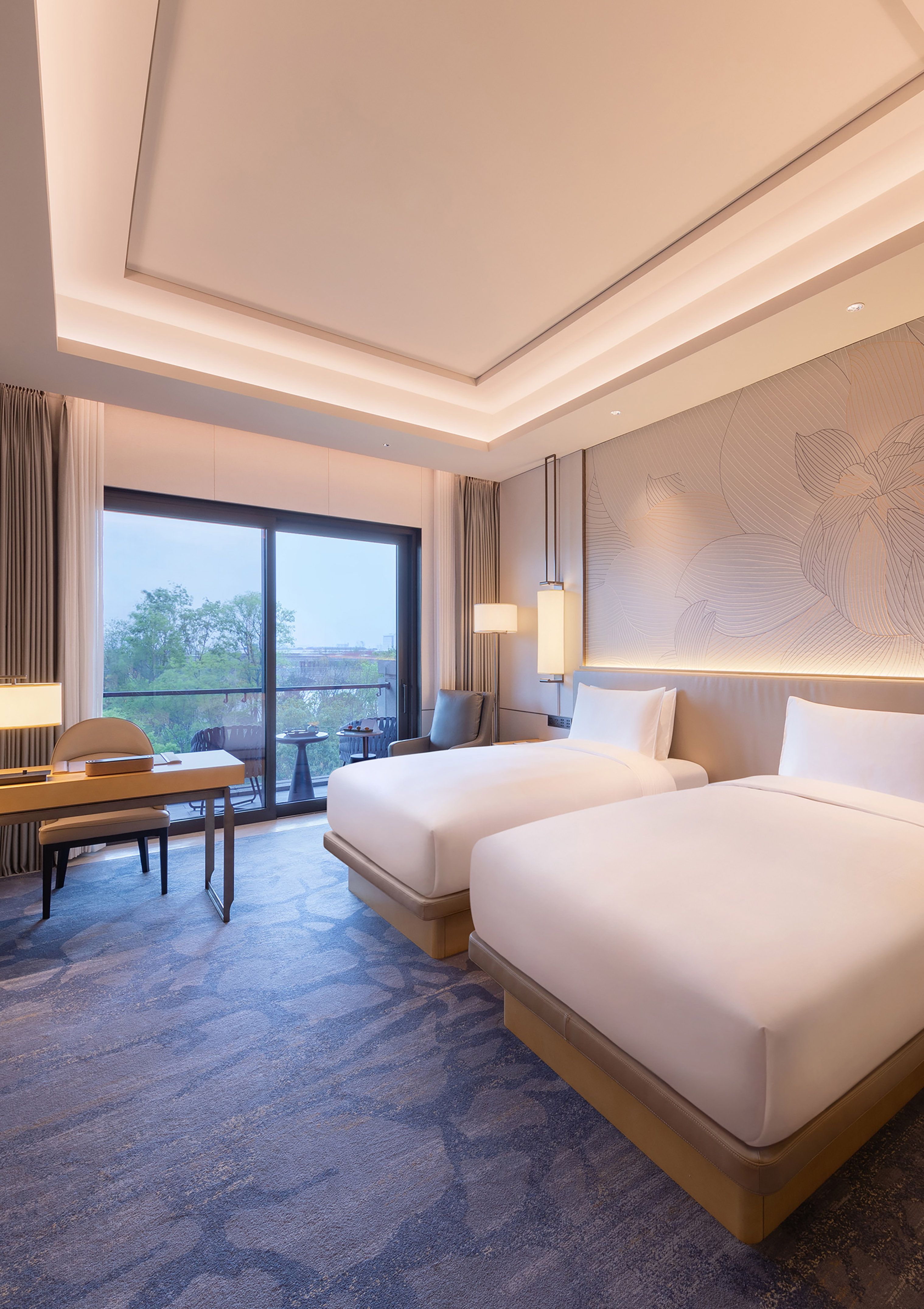 Luxury hotel room with two twin beds, work desk, and scenic balcony.