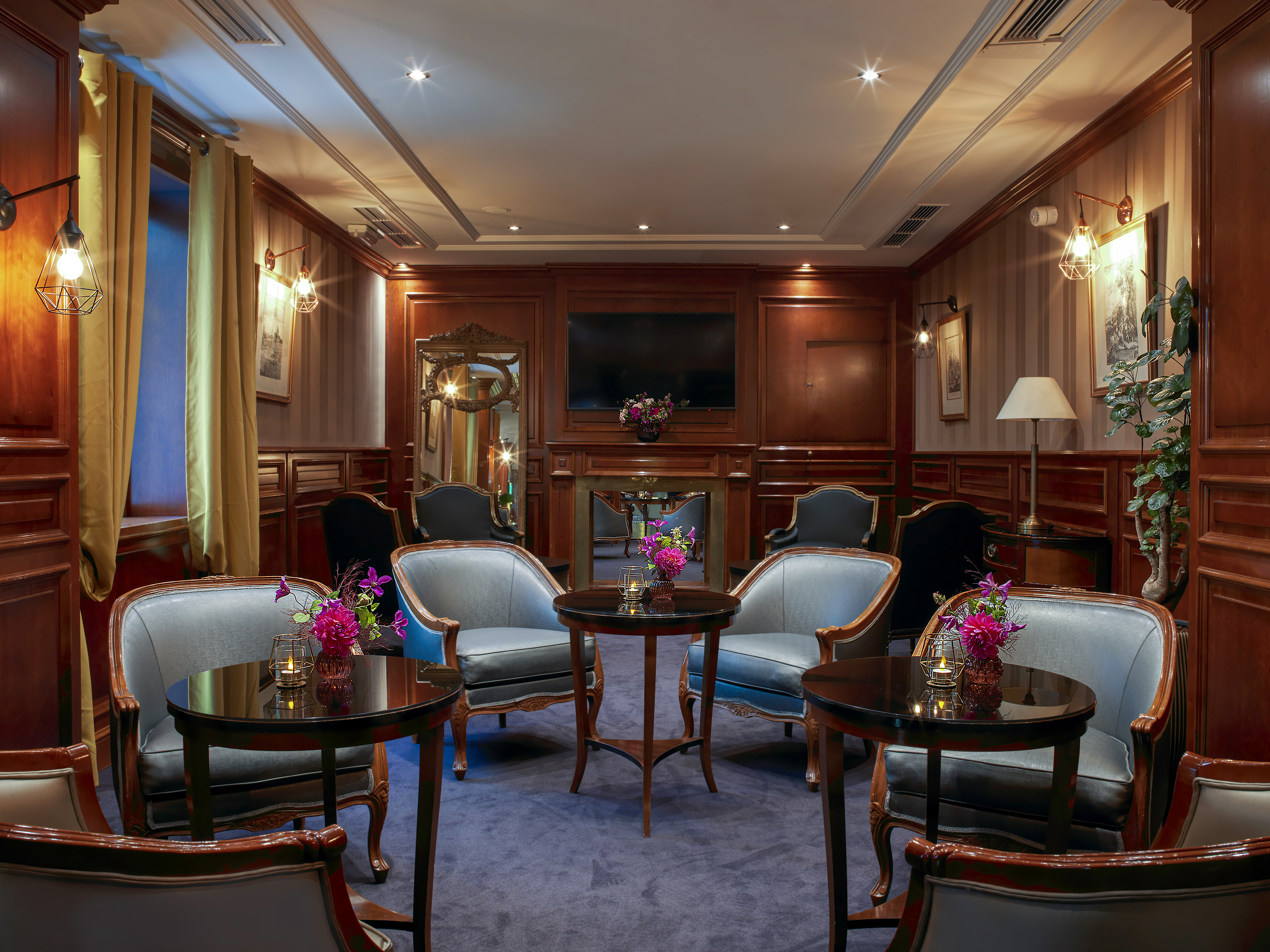 Elegant hotel lounge with classic armchairs, wood paneling, and fireplace.
