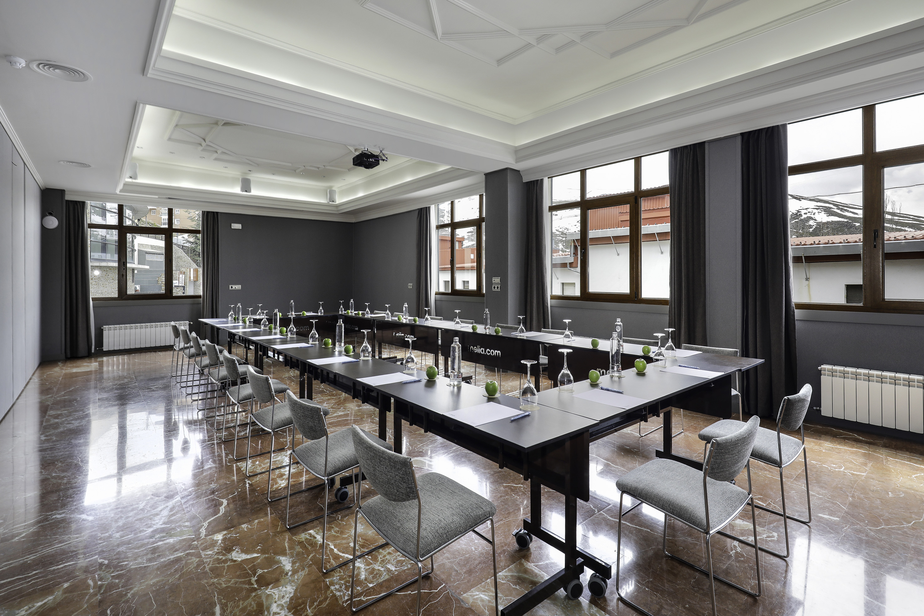 U-shaped conference room with projector, modern seating, large windows, and marble floor.