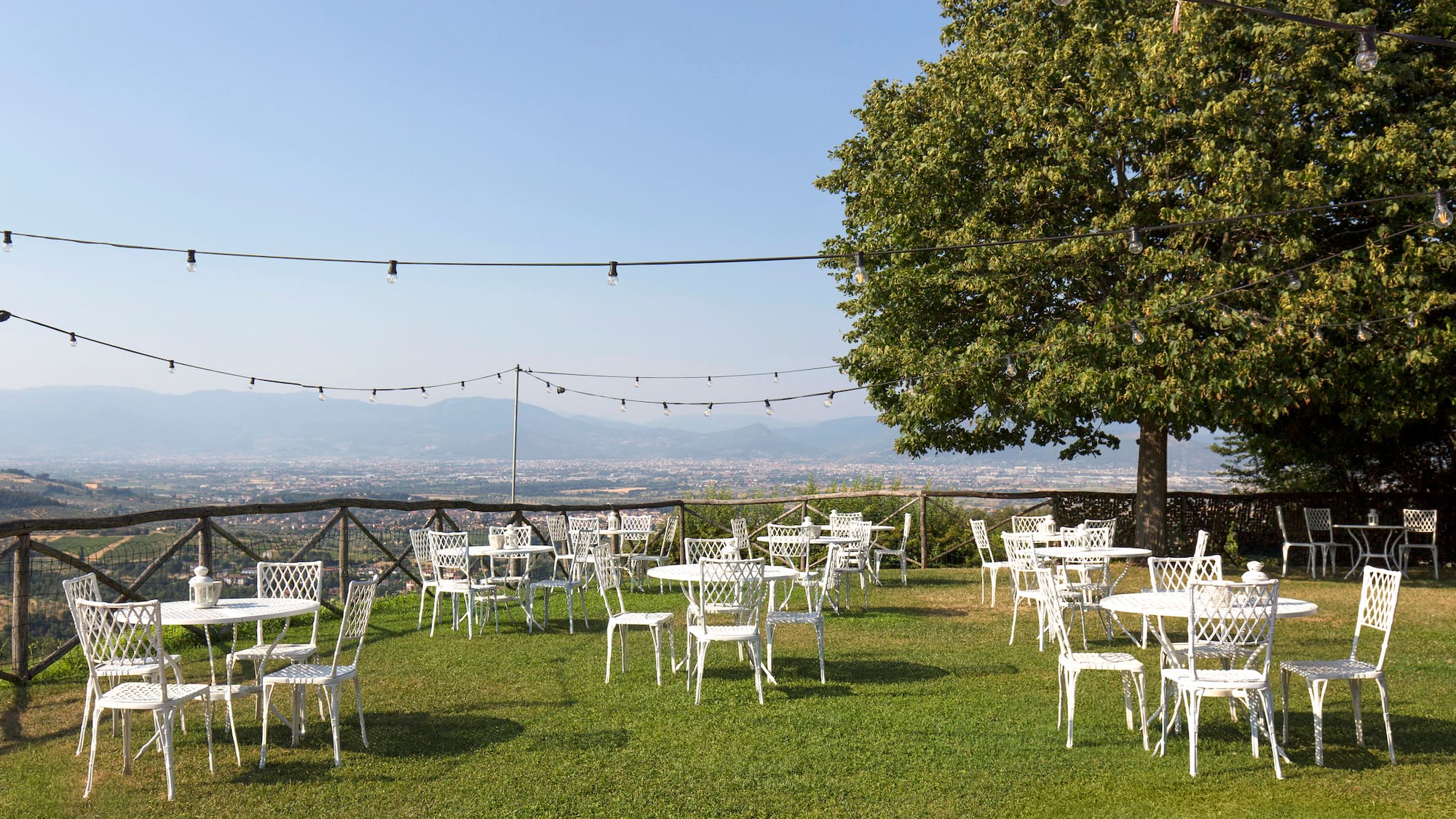 a group of white chairs and tables on a grassy area