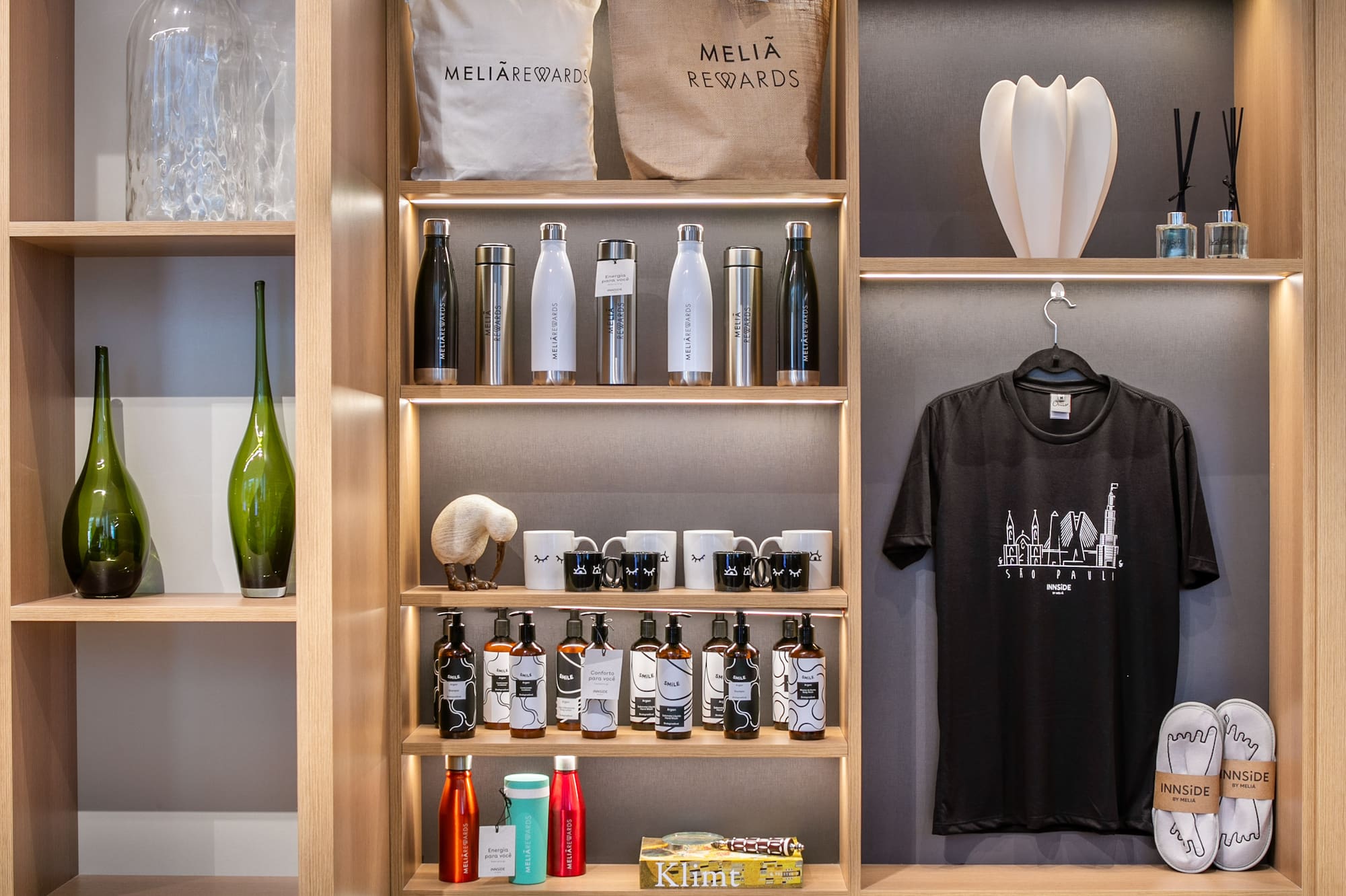 Meliá Rewards & Innside hotel merchandise on lit wooden display shelves.
