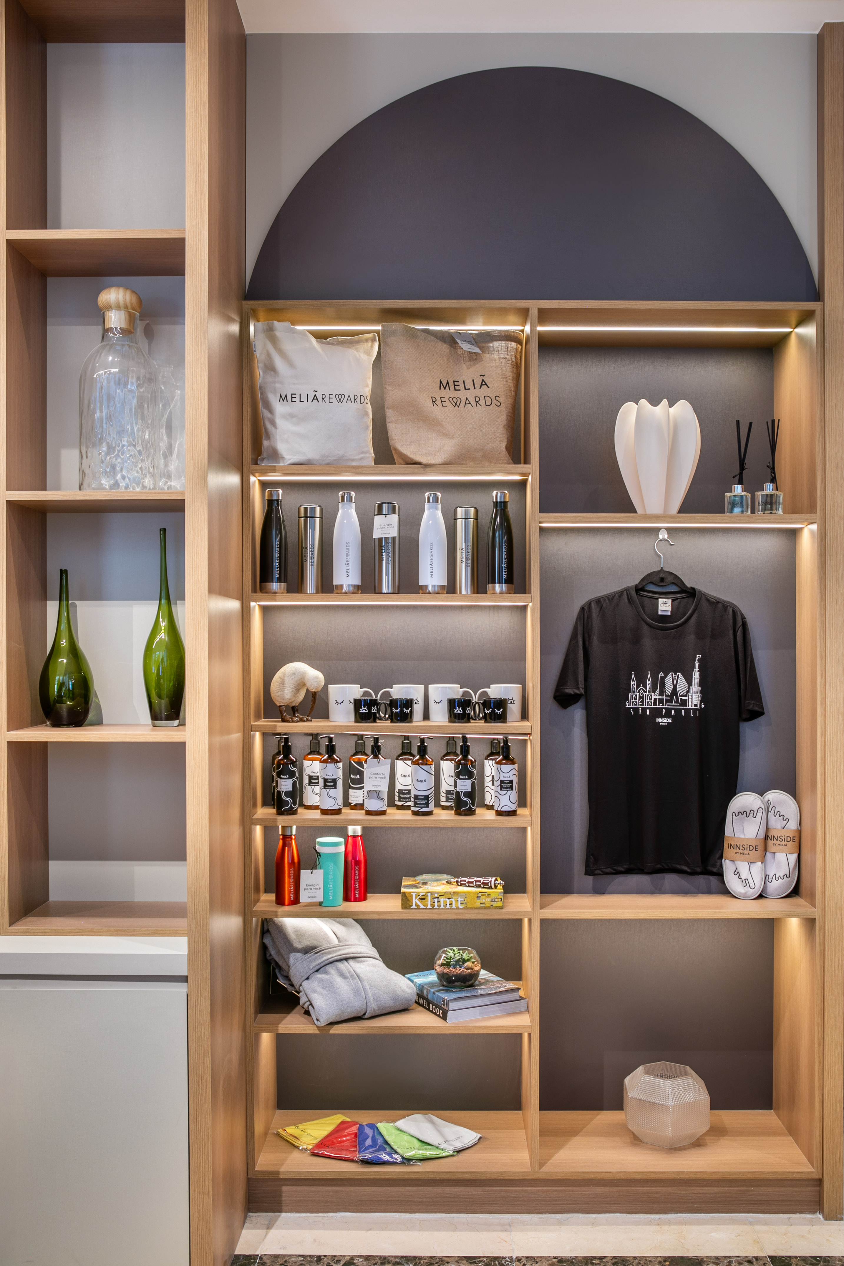 Meliá Rewards & Innside hotel merchandise on lit wooden display shelves.