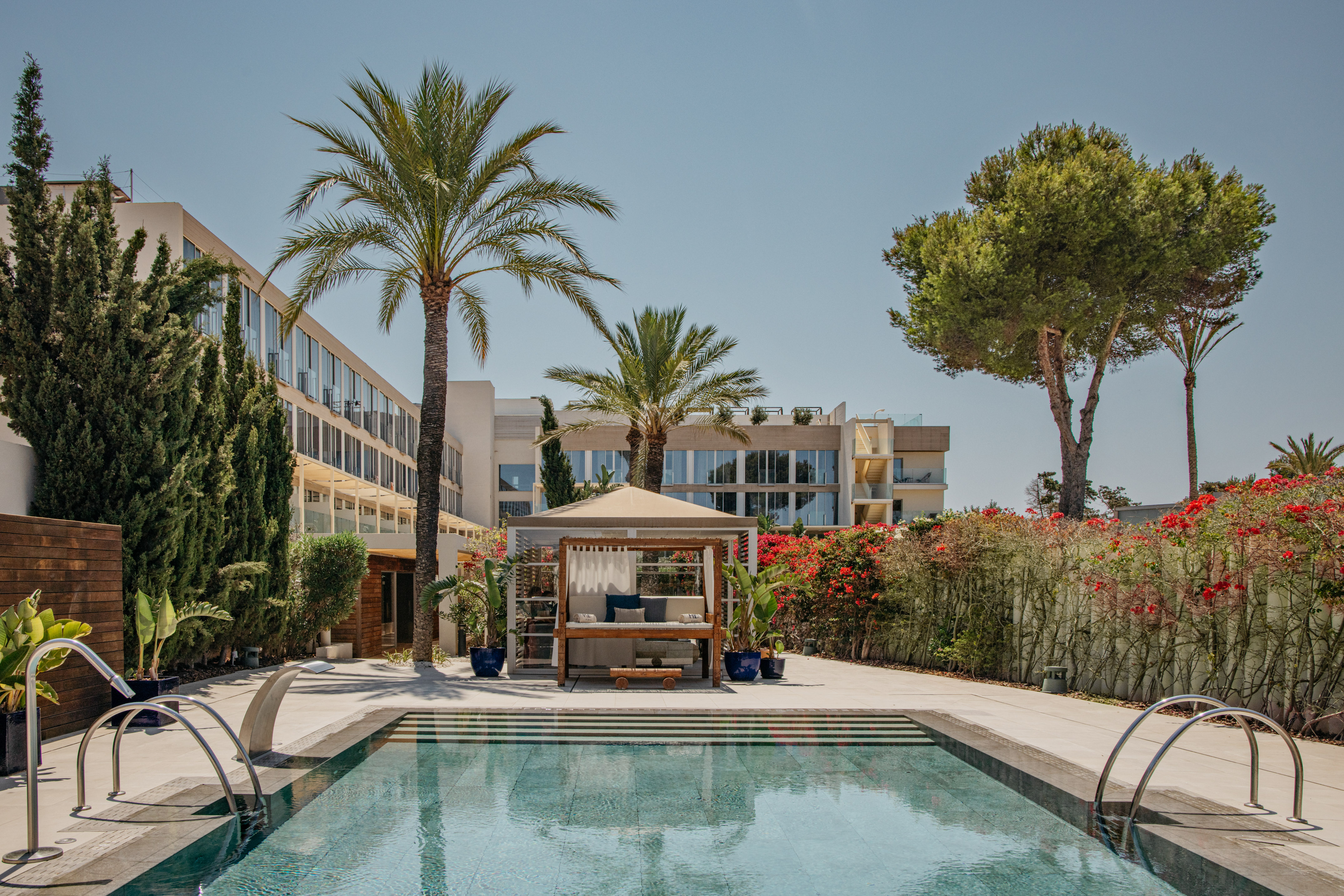 Luxury hotel swimming pool with cabana, palm trees, and modern architecture.