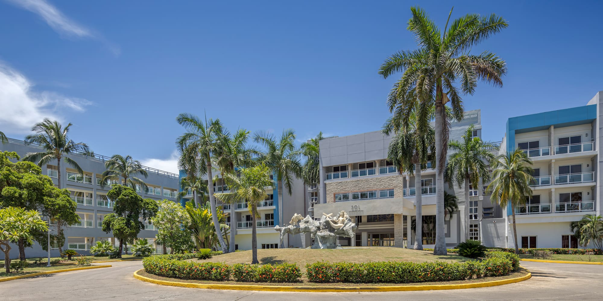 a building with palm trees and a circular driveway