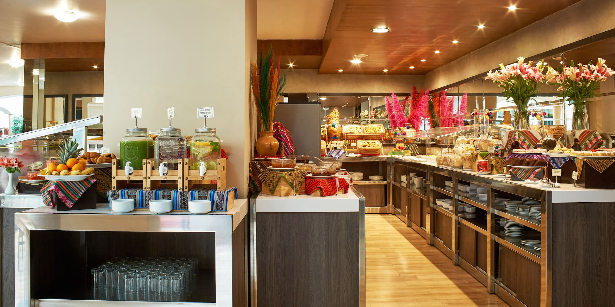 Colorful hotel breakfast buffet with juices, fresh fruits, and diverse dishes.