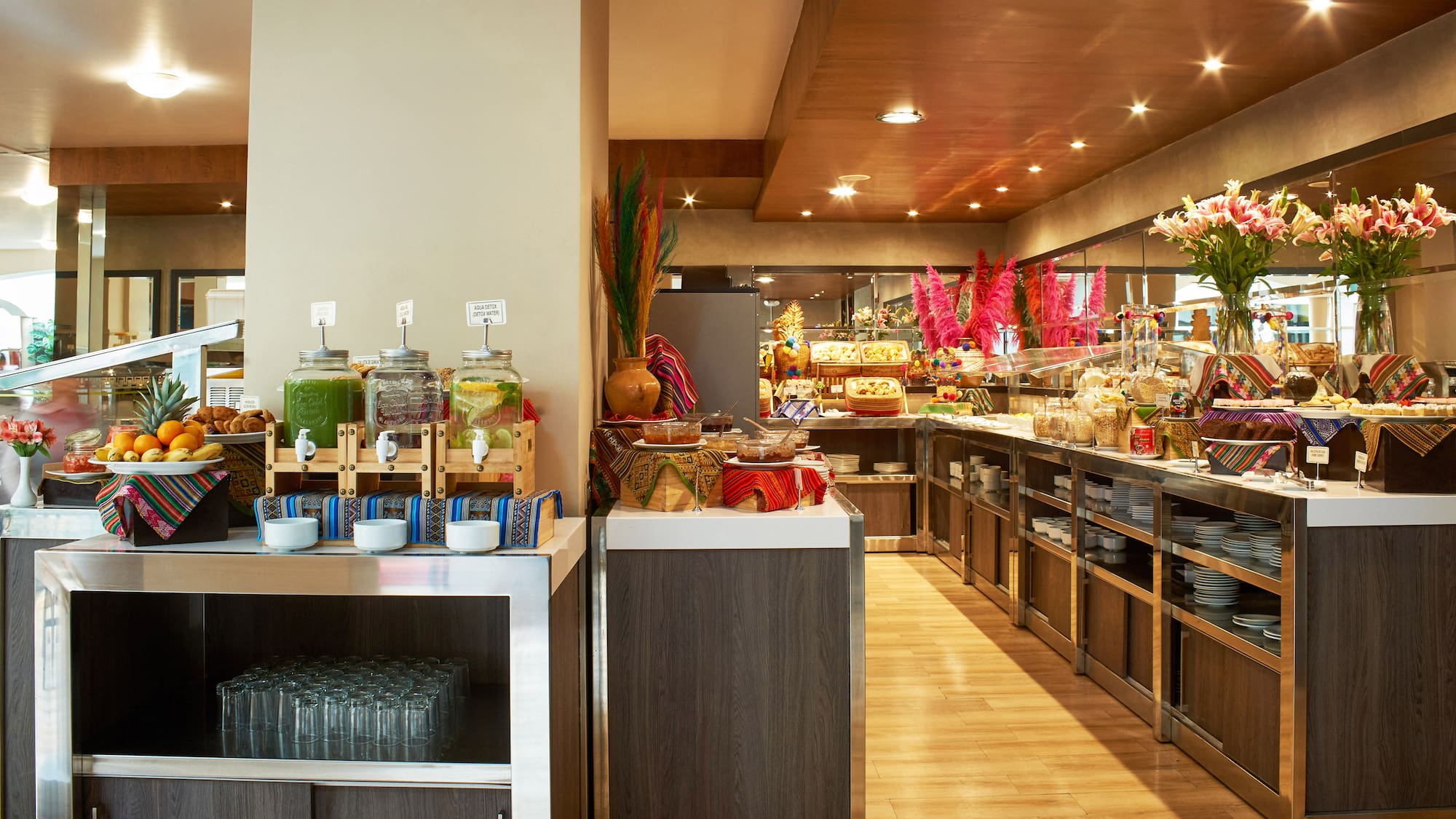 Colorful hotel breakfast buffet with juices, fresh fruits, and diverse dishes.