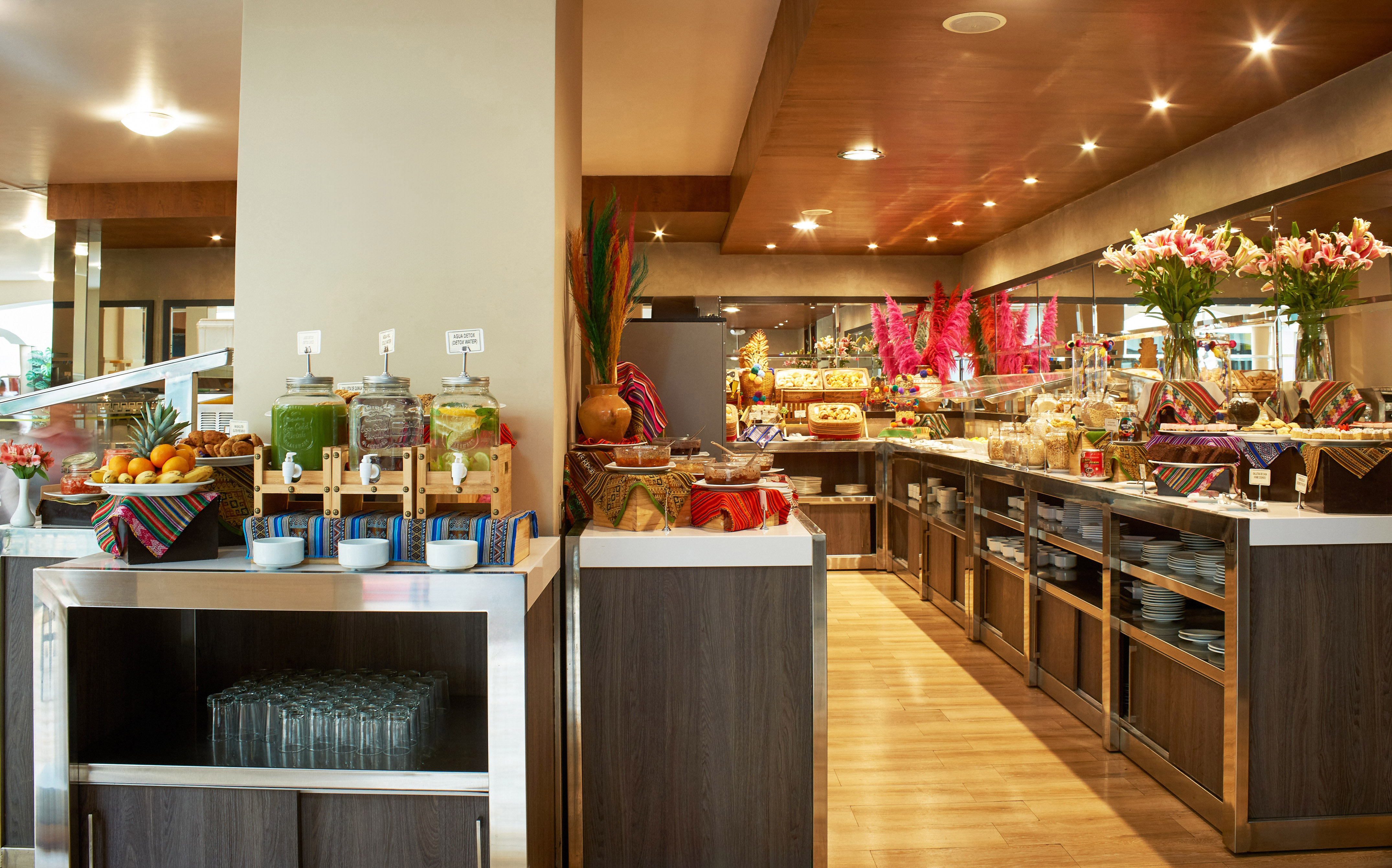 Colorful hotel breakfast buffet with juices, fresh fruits, and diverse dishes.