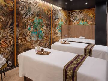 a room with two beds and a wall with art on the wall