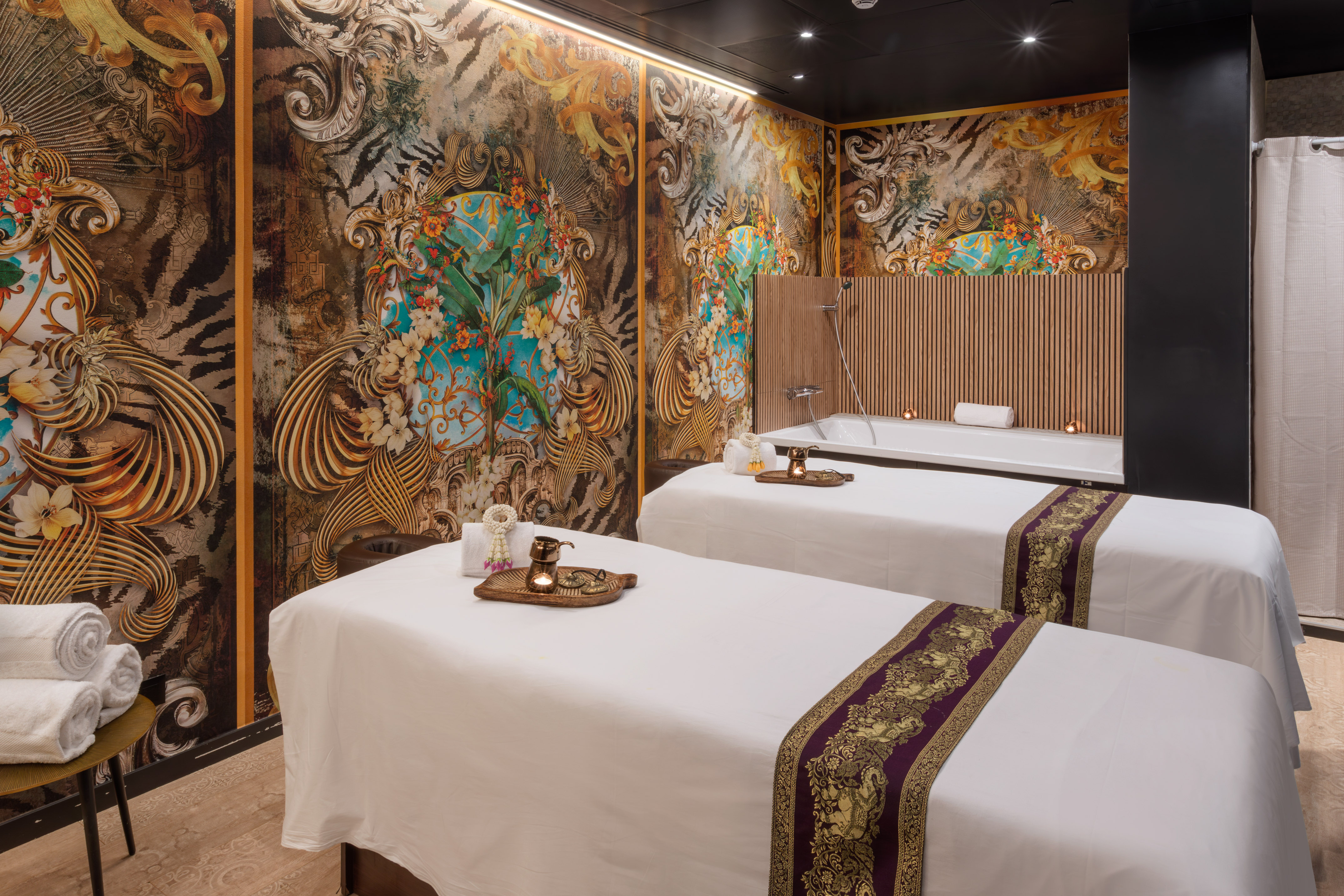 Luxury spa room with two massage beds, tub, and ornate jungle decor.