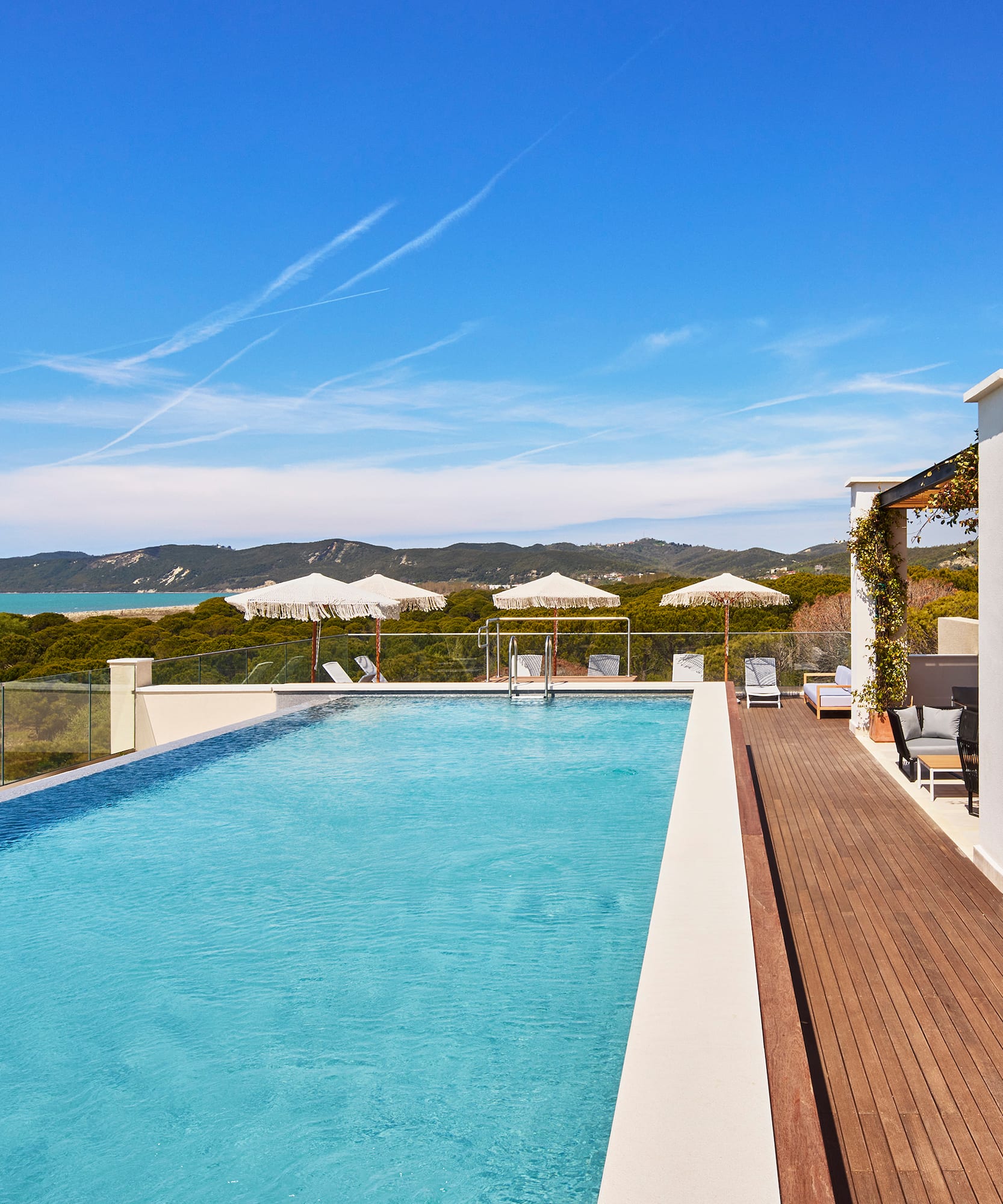 a swimming pool with a deck and a building with trees in the background